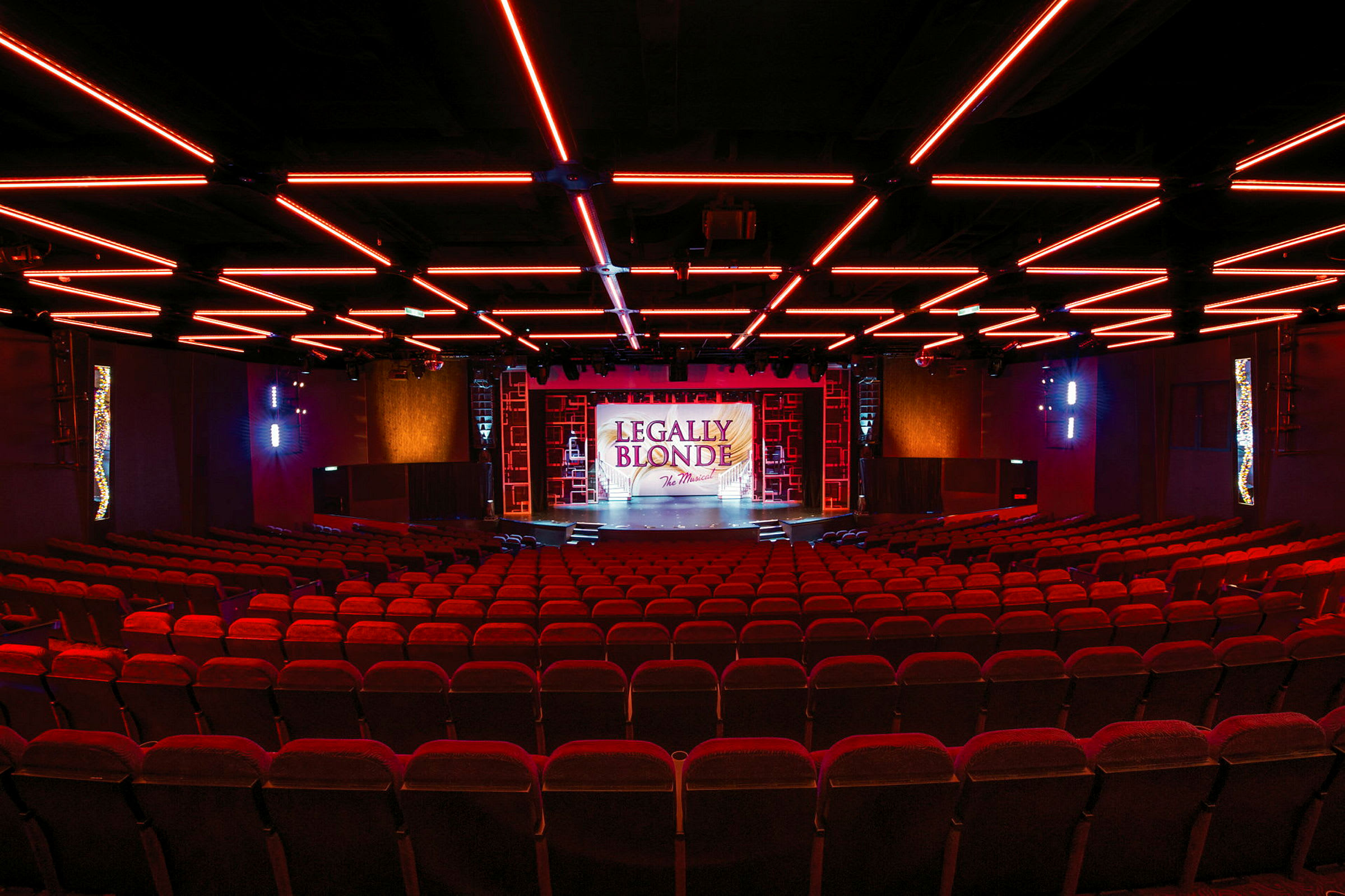 En teater med røde seter og en opplyst scene med teksten 'Legally Blonde'. (AI-generert tekst)