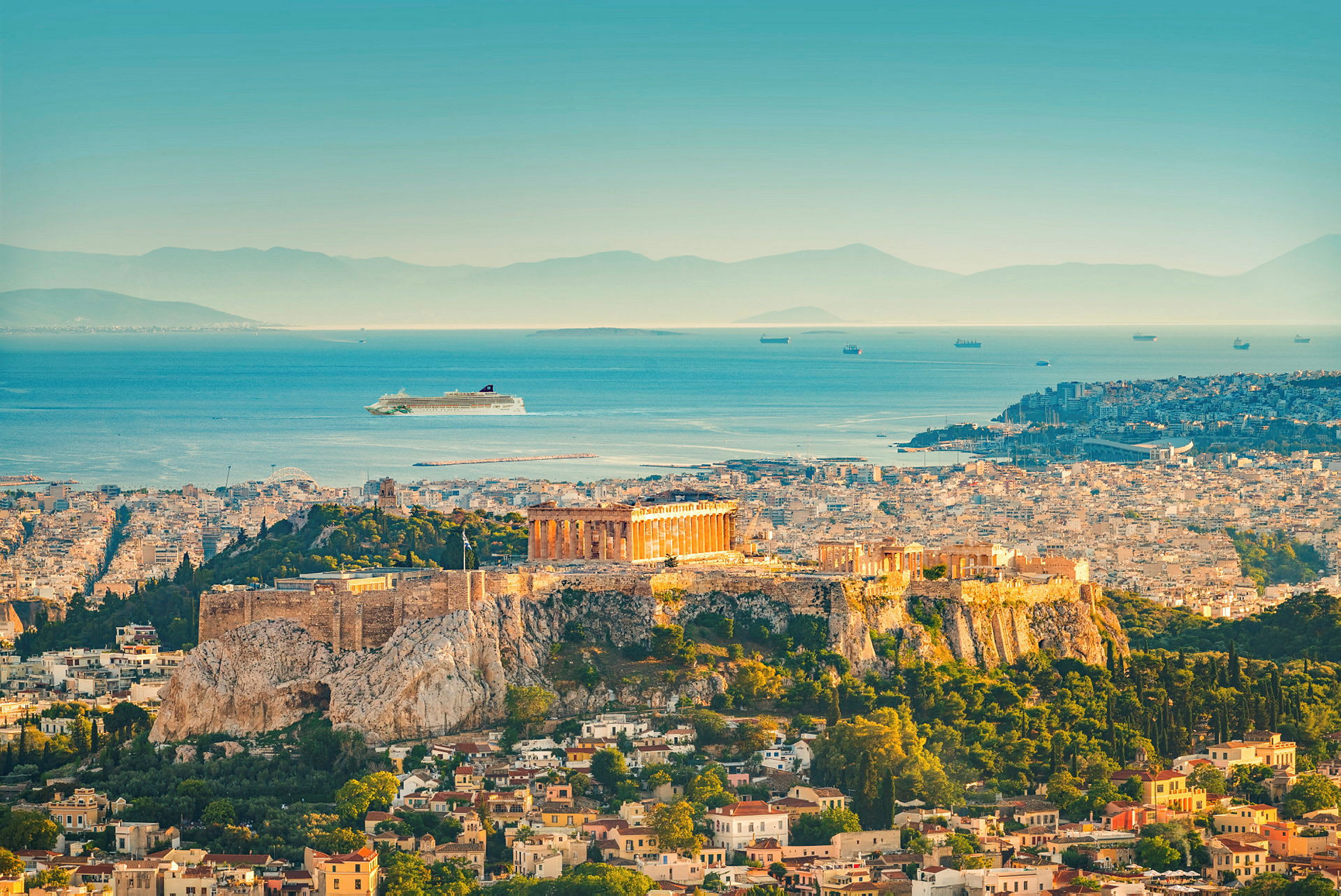 Bilde av Akropolis i Athen med Parthenon på en høyde over byen og havet i bakgrunnen. (AI-generert tekst)