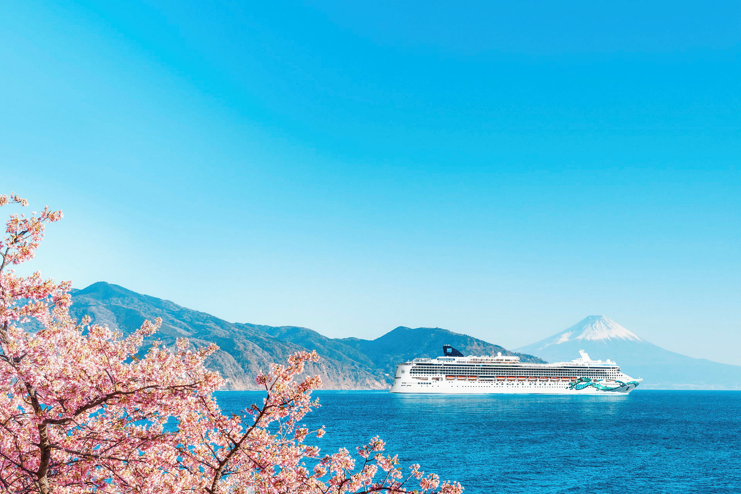 Et cruiseskip på en blå havutsikt med fjell og Mount Fuji i bakgrunnen, samt kirsebærblomster i forgrunnen. (AI-generert tekst)