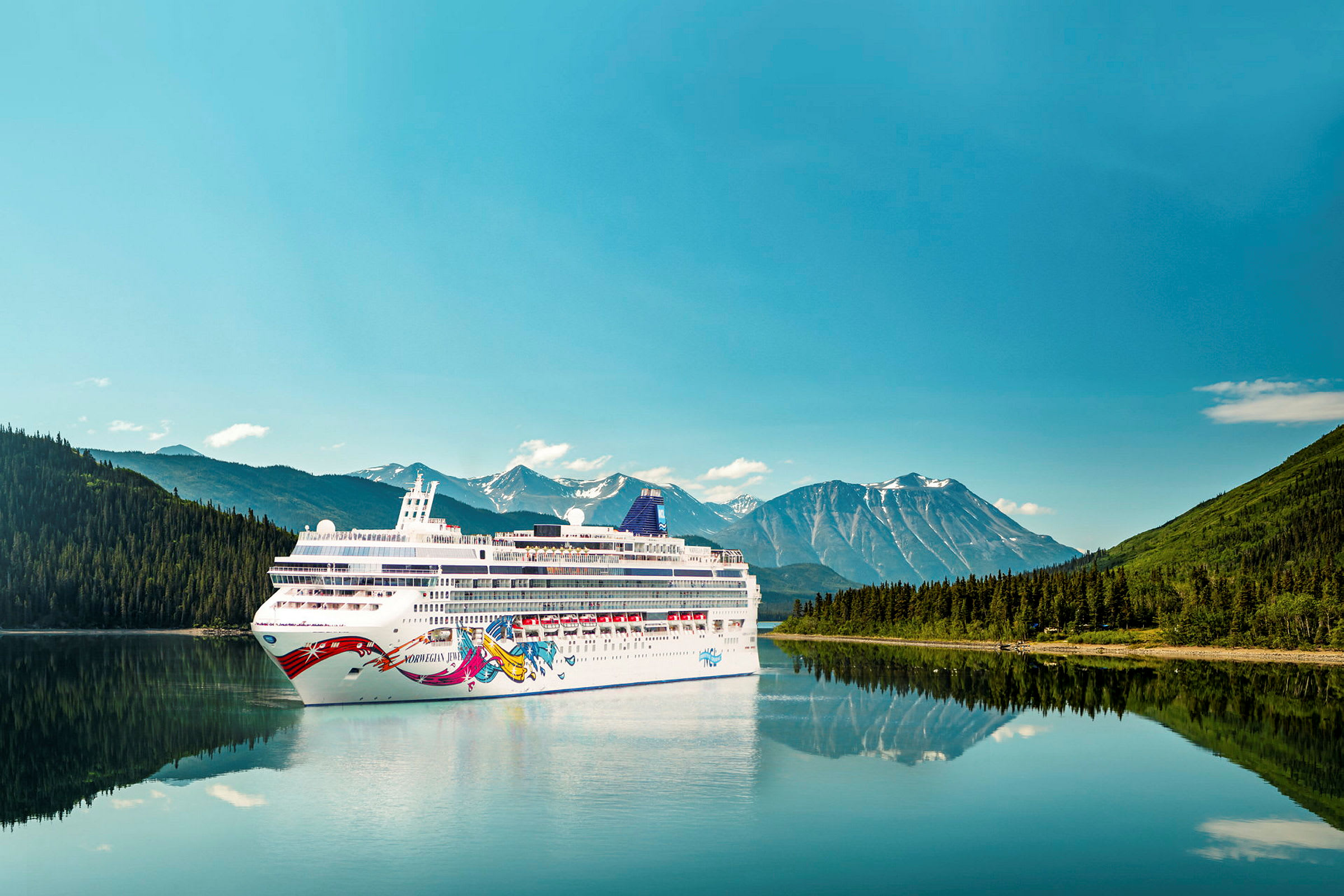 Cruiseskip på en innsjø med fjell og skog i bakgrunnen. (AI-generert tekst)