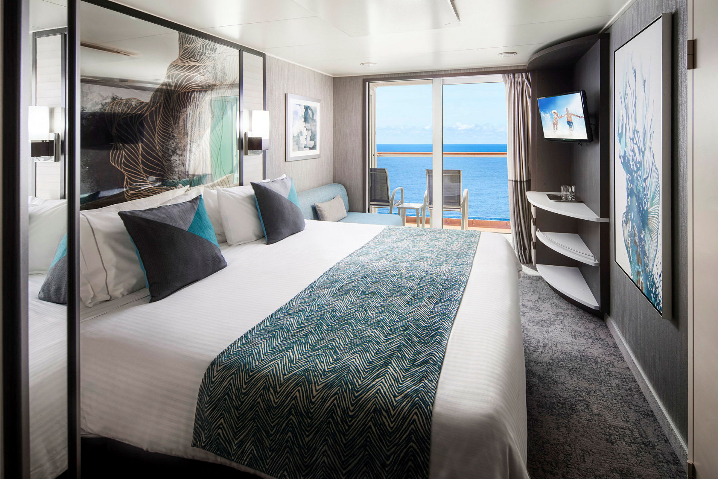 Hotellrom med dobbeltseng, puter og utsikt mot havet gjennom glassdører. (AI-generert tekst)