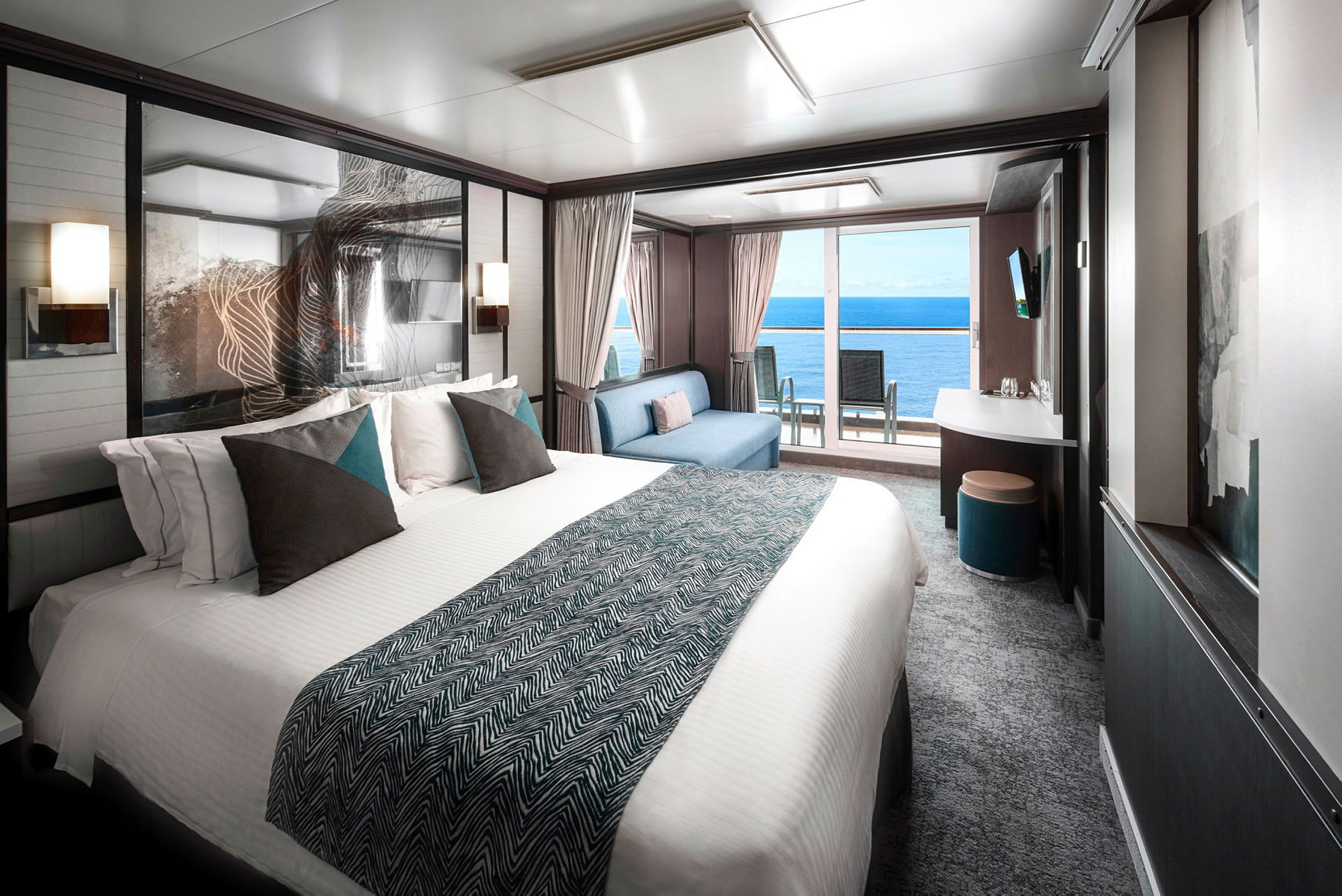 Bilde av et moderne hotellrom med en stor seng, en sittegruppe og utsikt over havet gjennom store vinduer. (AI-generert tekst)