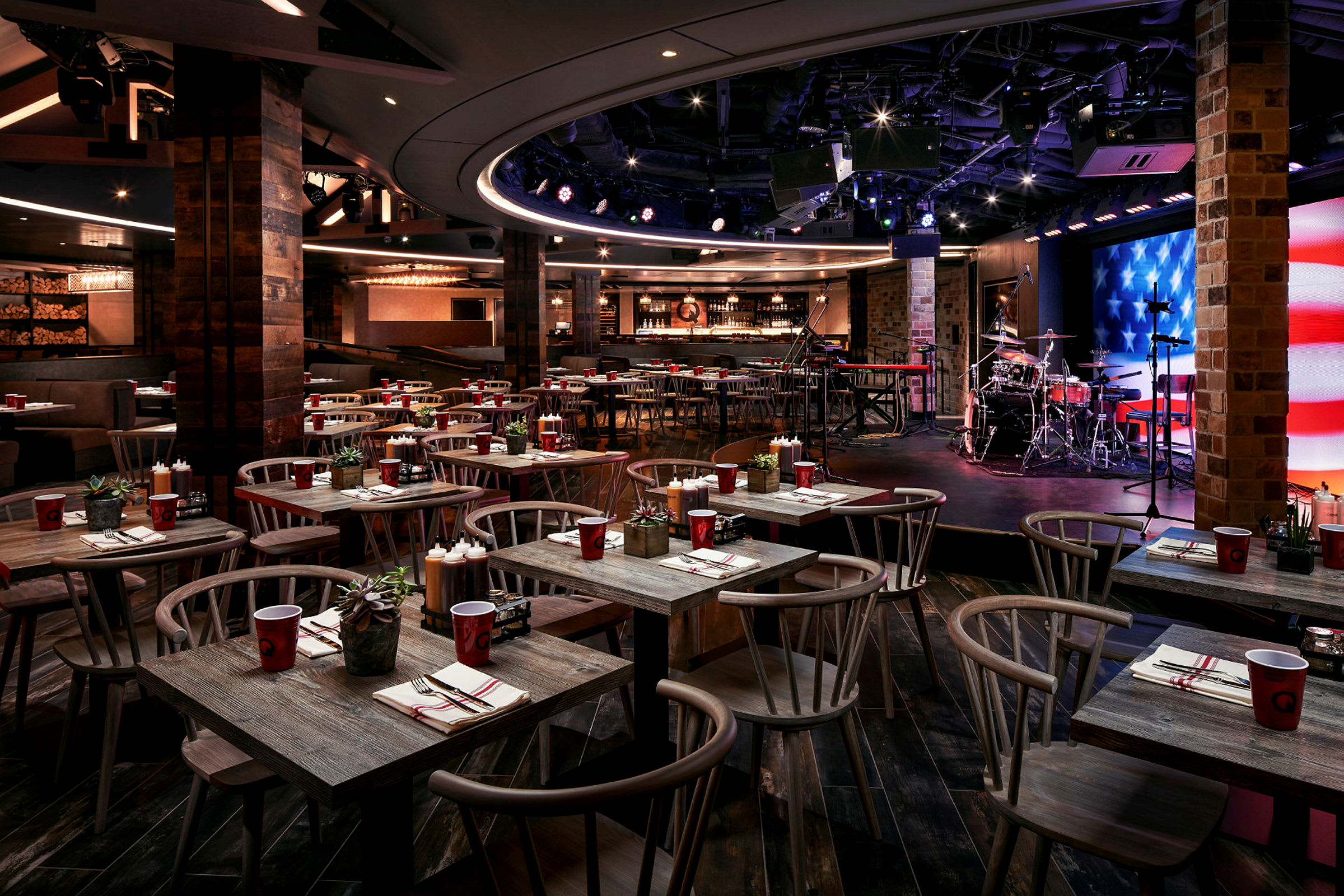 En restaurant med bord og stoler samt en scene med musikkinstrumenter. (AI-generert tekst)