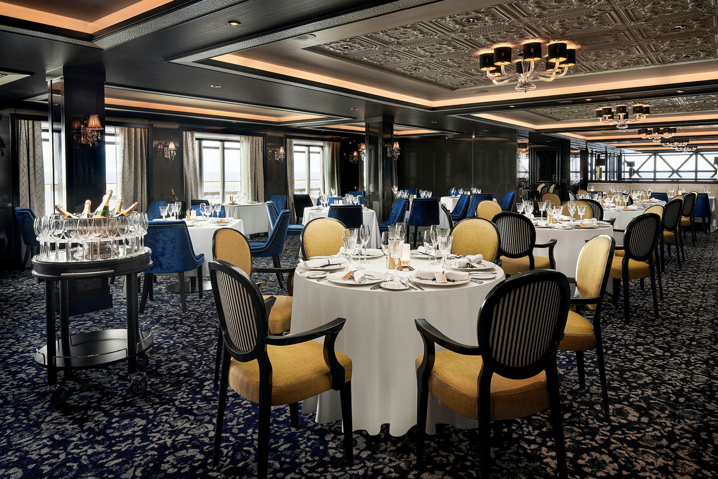 Bilde av en elegant restaurant med dekkede bord, komfortable stoler og en serveringsvogn med glass og flasker. (AI-generert tekst)