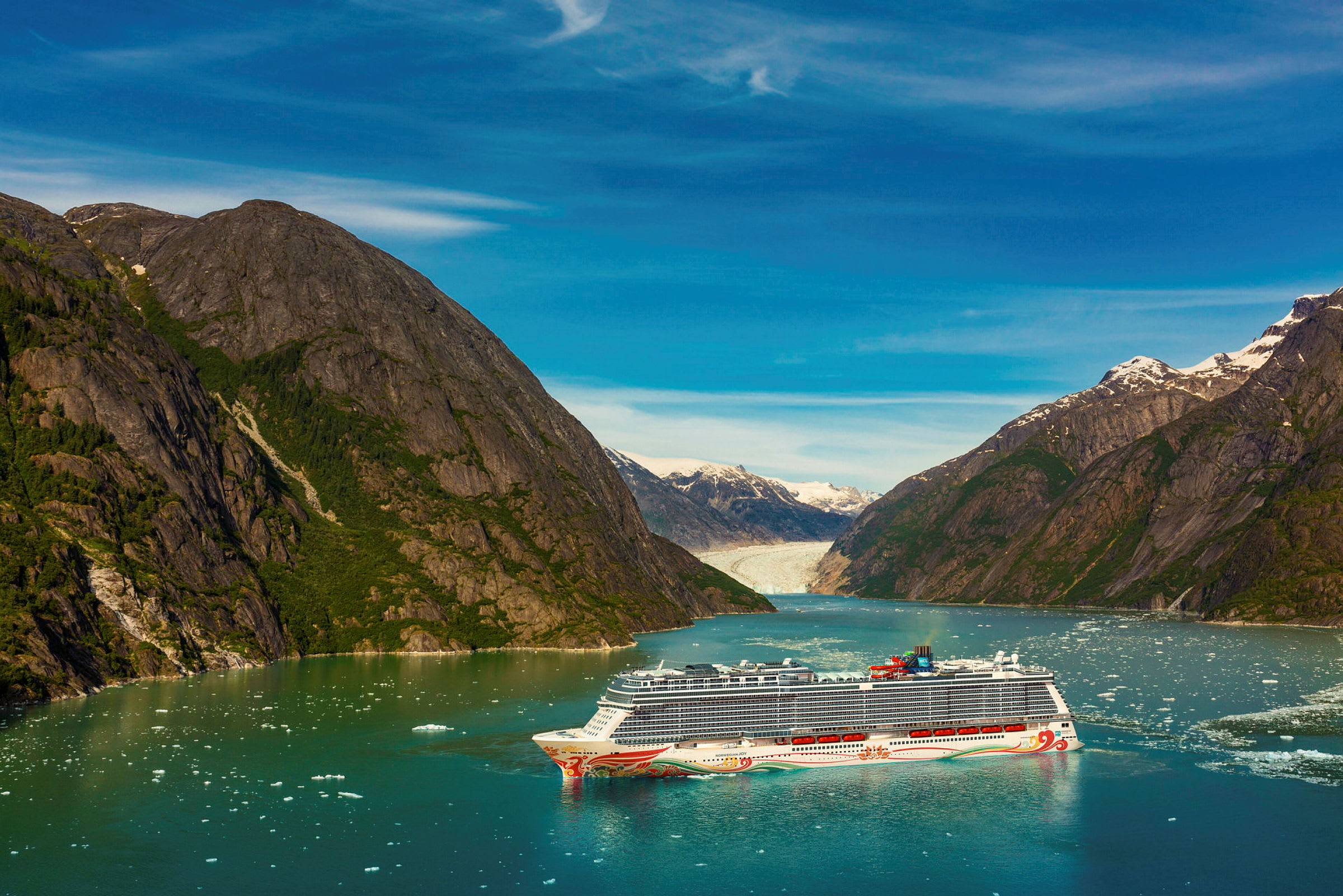 Cruiseskip i en fjord med omkringliggende fjell og isbre i bakgrunnen. (AI-generert tekst)
