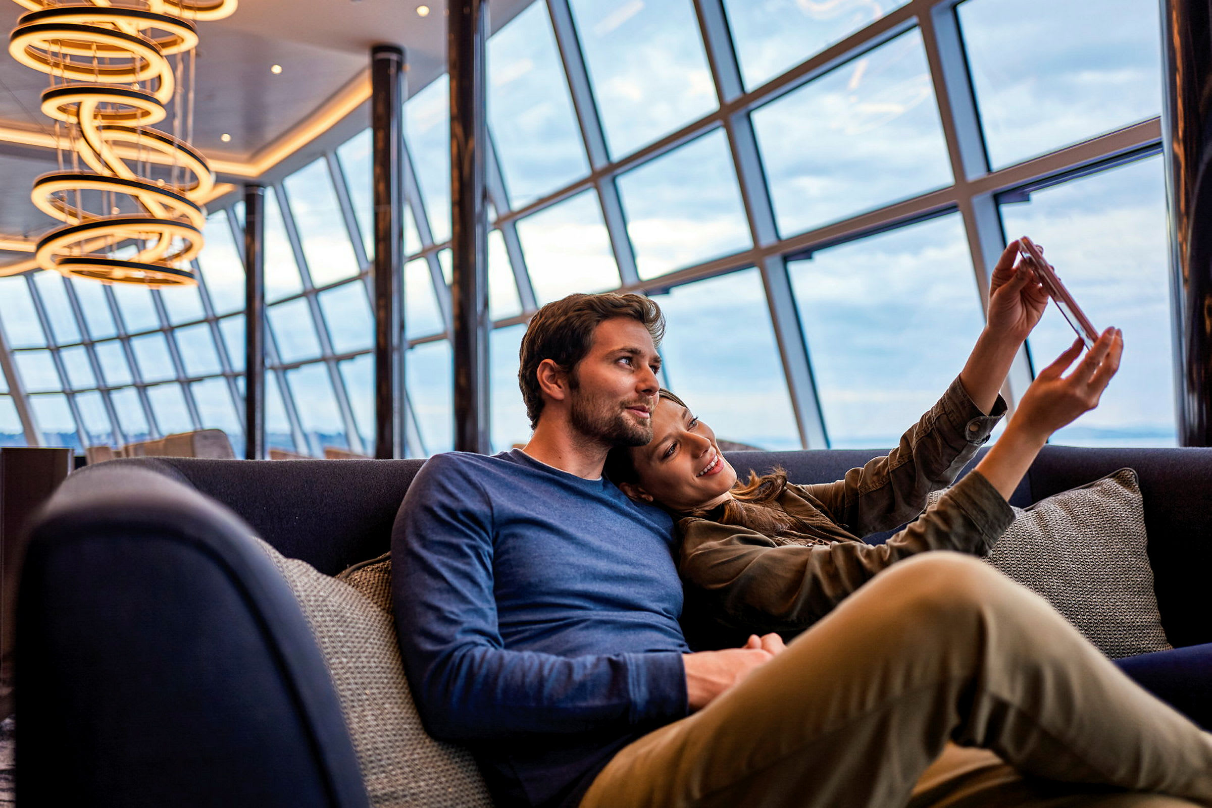 En moderne lounge med store vinduer og hengende lysekroner. (AI-generert tekst)
