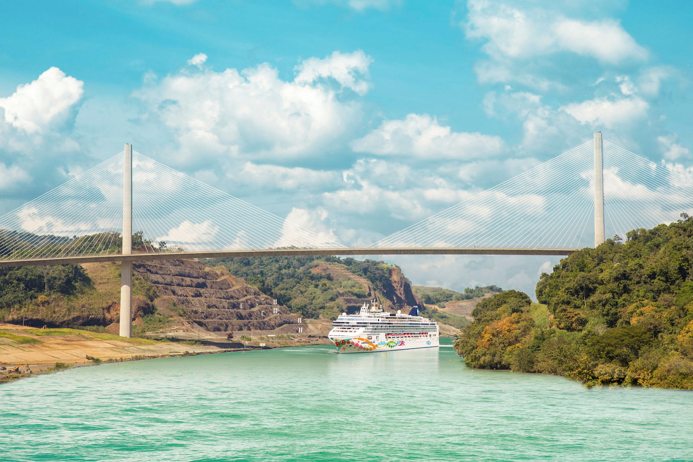 Bilde av et cruiseskip som passerer under en stor hengebro over en kanal. (AI-generert tekst)