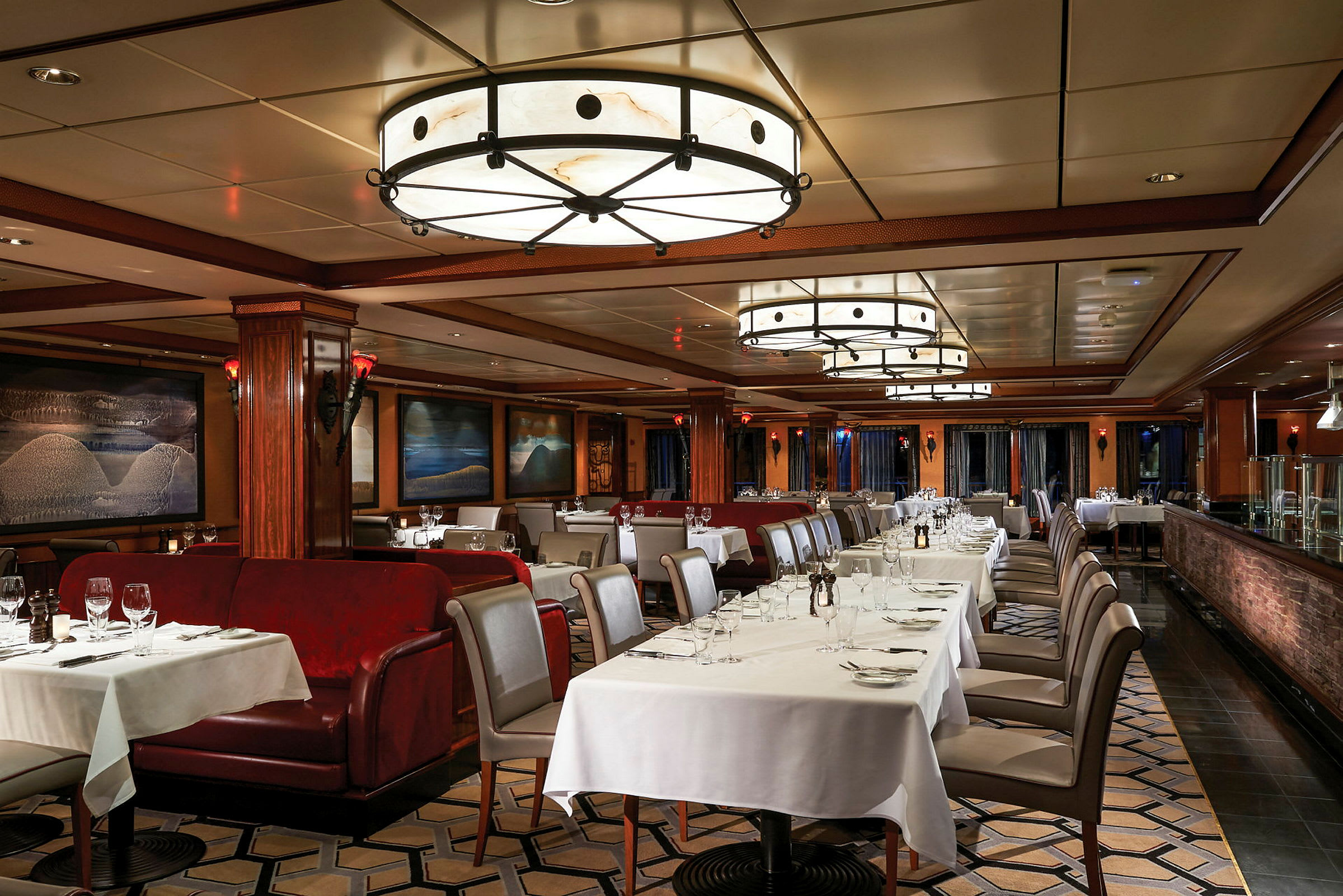 Elegant restaurant med bord og stoler dekket med hvite duker og røde stoppede sofaer. (AI-generert tekst)