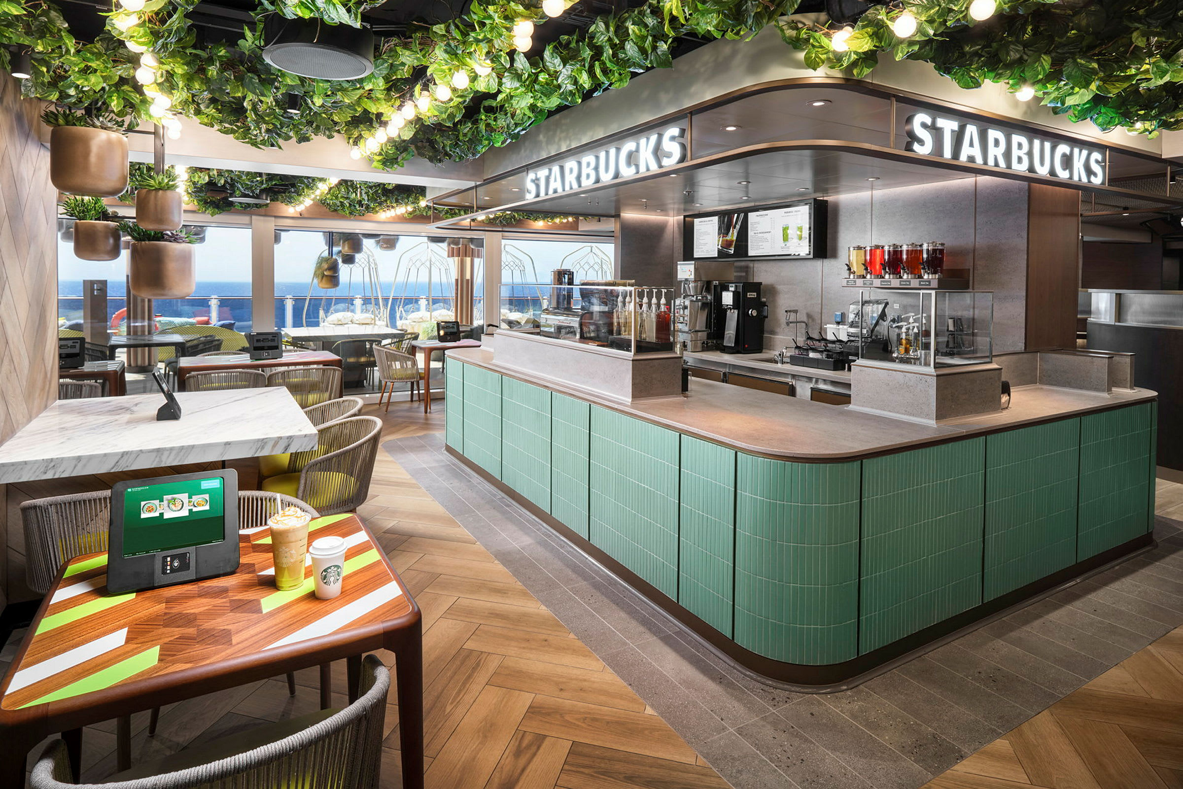 En Starbucks-butikk med havutsikt, grønt interiør og sitteplasser. (AI-generert tekst)