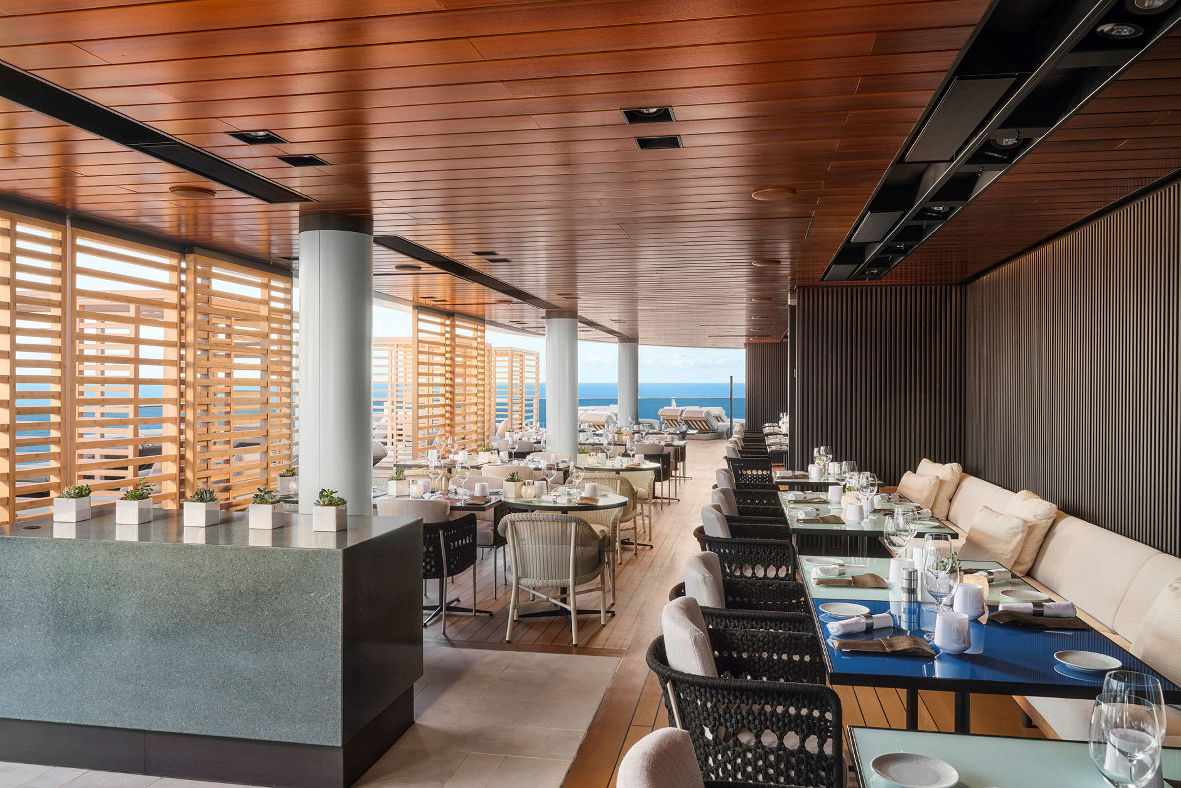 En elegant restaurant med havutsikt, innendørs og utendørs områder, med tretitaljer og moderne interiør. (AI-generert tekst)