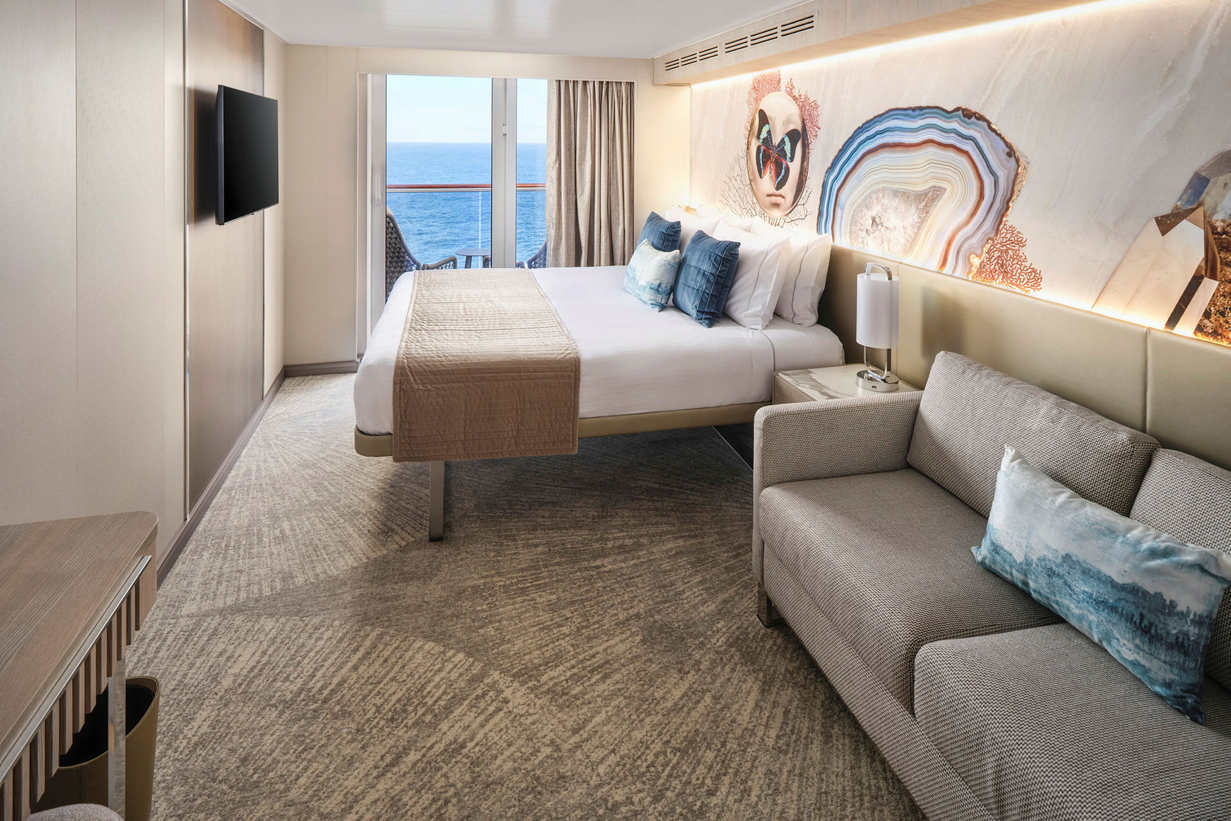 Interiørbilde av et hotellrom med en dobbeltseng, sofa og en balkong med utsikt over havet. (AI-generert tekst)