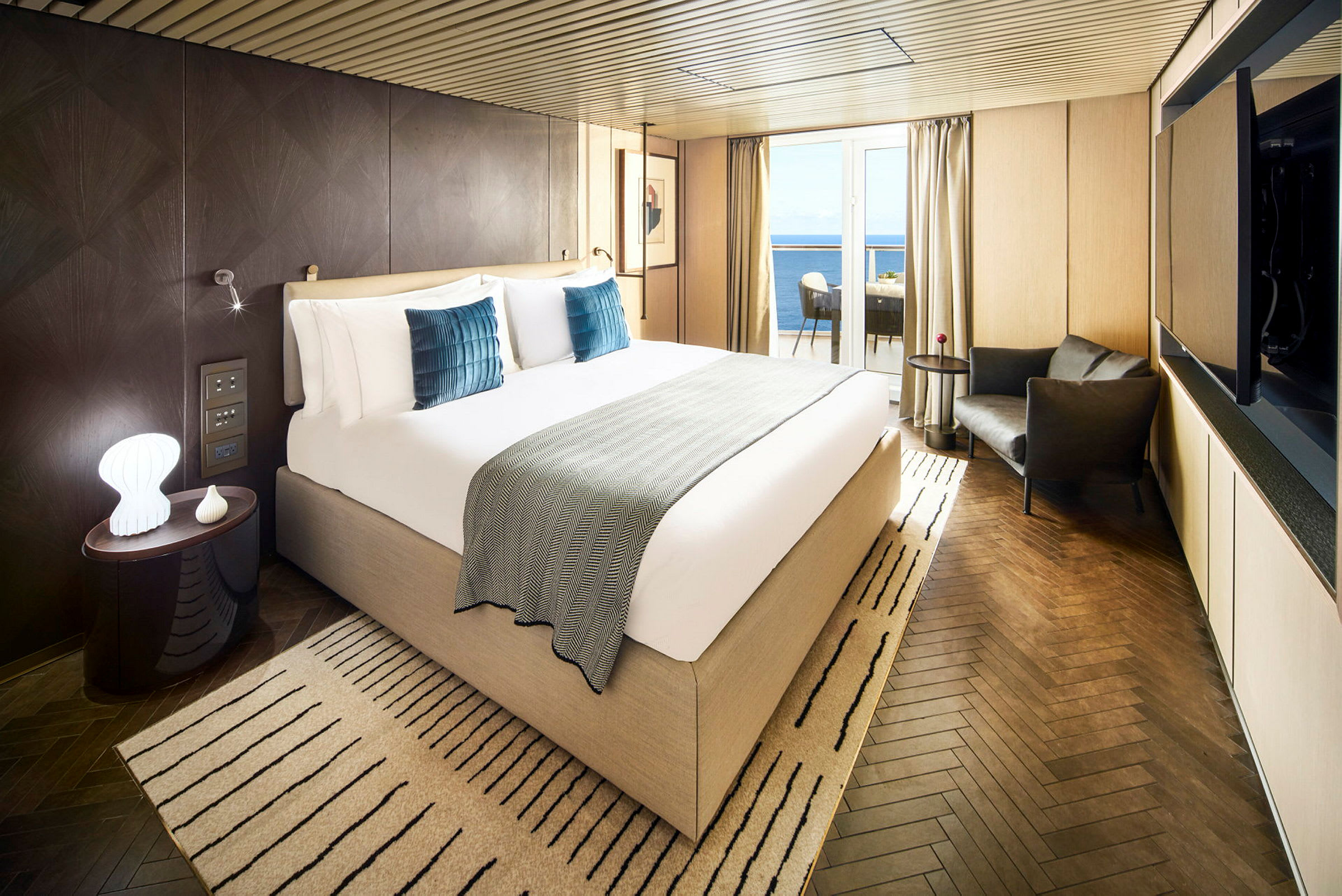 Hotellrom med stor seng, sitteområde og balkong med utsikt over havet. (AI-generert tekst)
