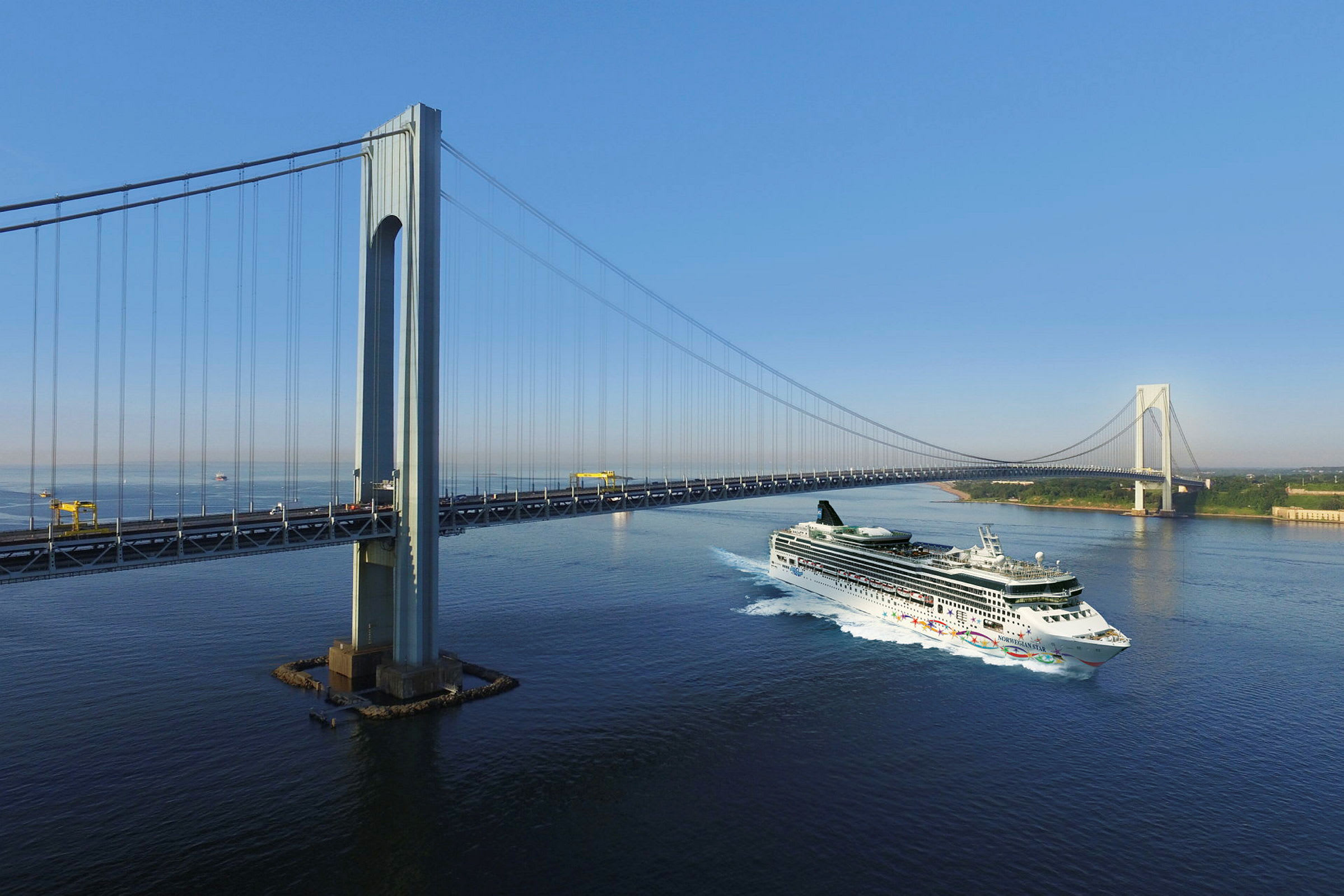 Et cruiseskip passerer under en stor hengebro over havet. (AI-generert tekst)