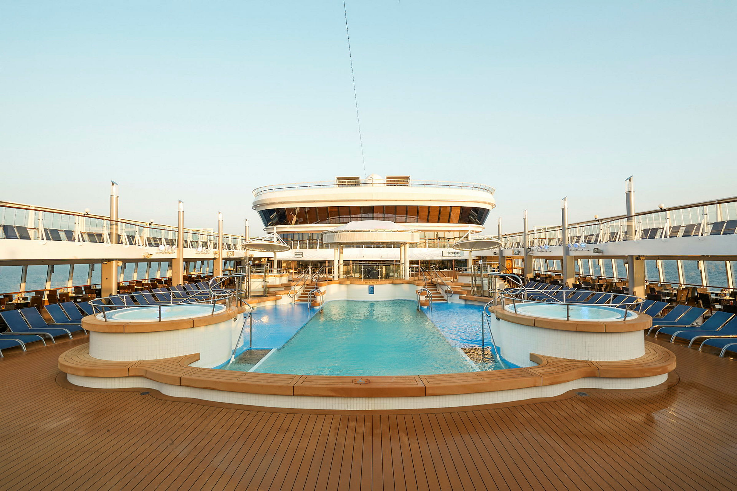 Utsikt over det øvre dekket på et cruiseskip med basseng og solsenger. (AI-generert tekst)