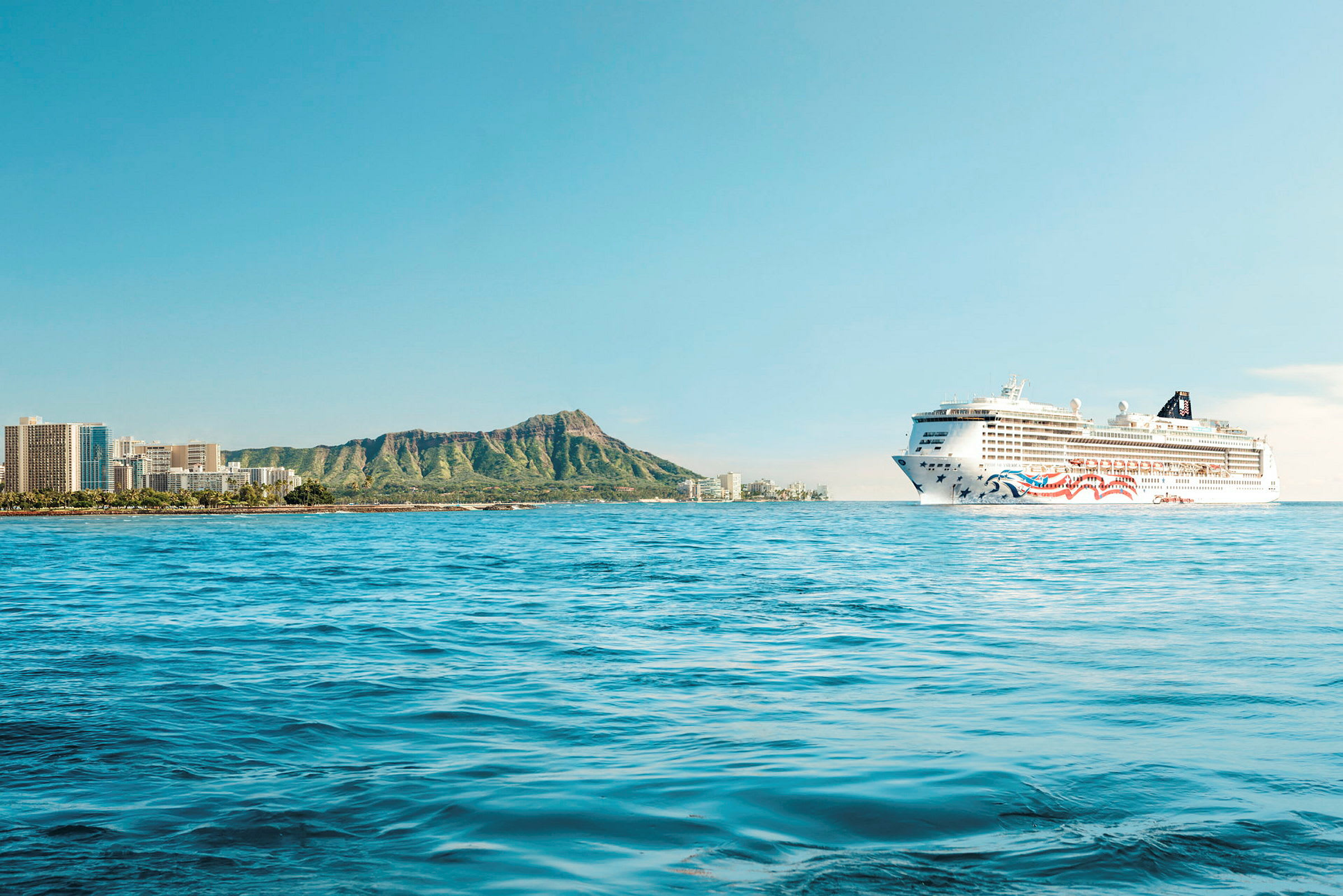 Et cruiseskip seiler nær en kystlinje med fjellkjede og bygninger. (AI-generert tekst)