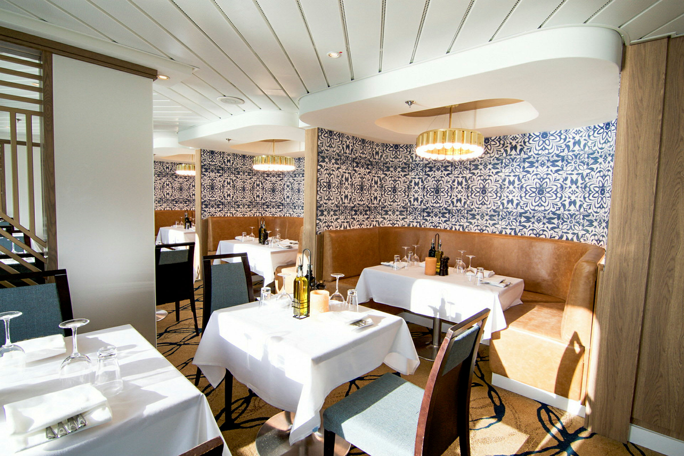 En elegant restaurant med hvite duker, blåmønstrede tapeter og moderne lysekroner. (AI-generert tekst)