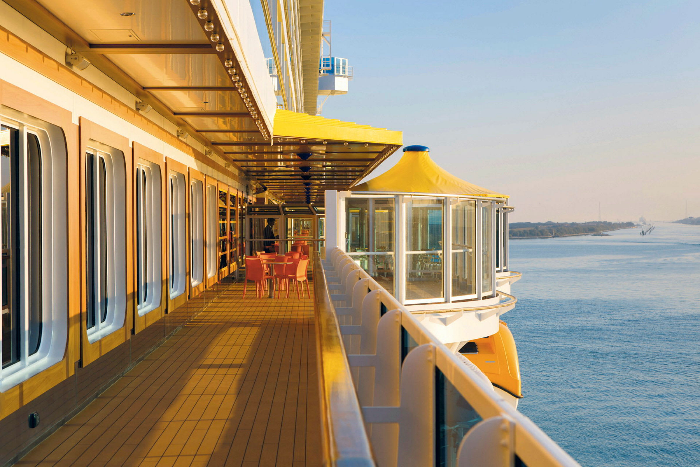 Et cruiseskips utvendige promenade dekk med sitteplasser og utsikt over vannet. (AI-generert tekst)