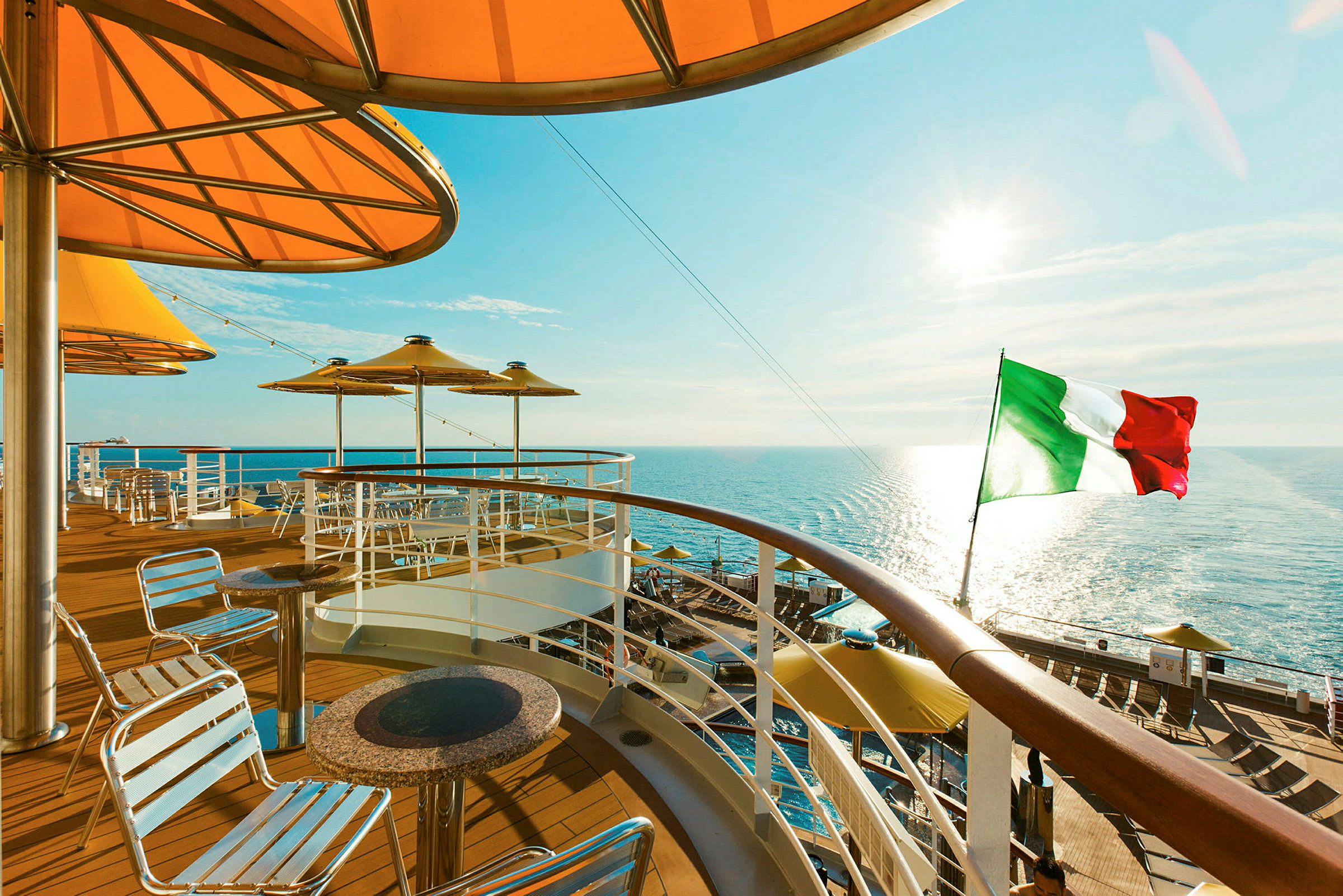 Utsikt fra dekk på et cruiseskip med utsikt over havet og det italienske flagget. (AI-generert tekst)