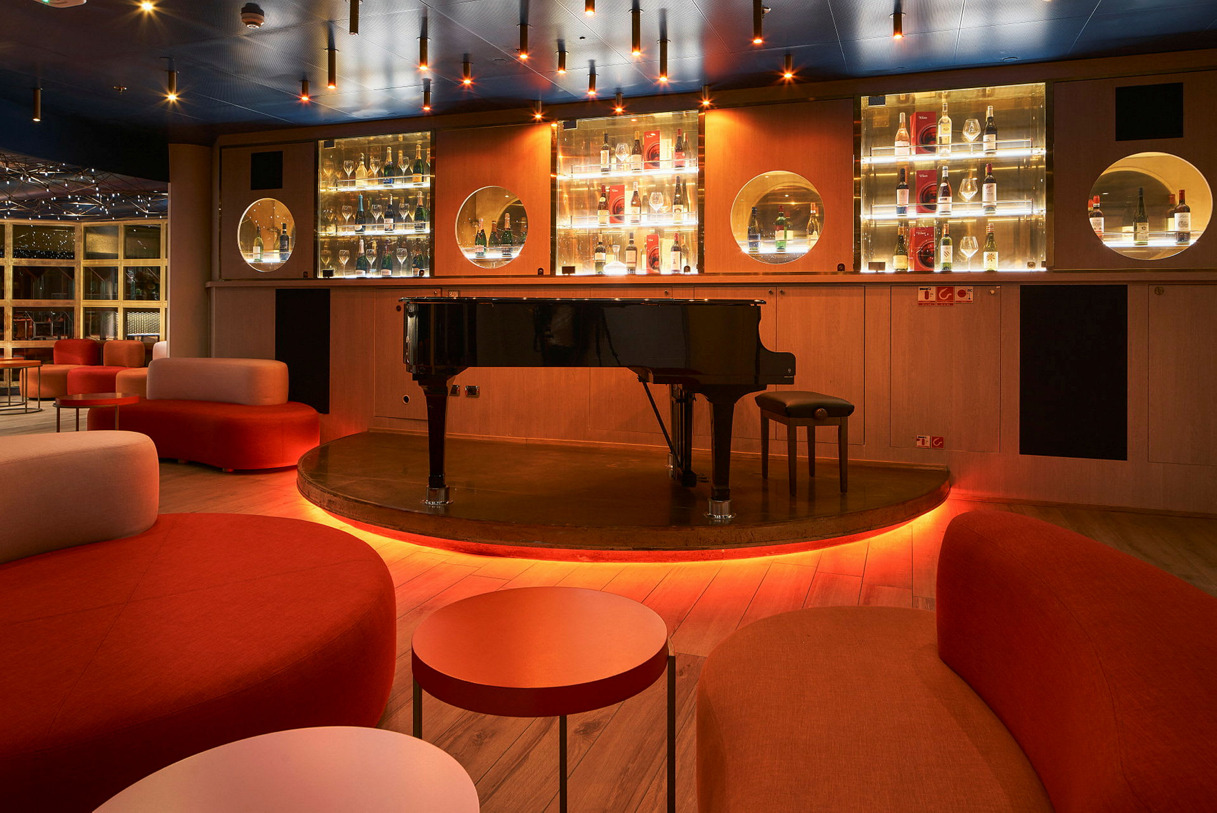 Et svart flygel på en opplyst scene i et moderne loungeområde. (AI-generert tekst)