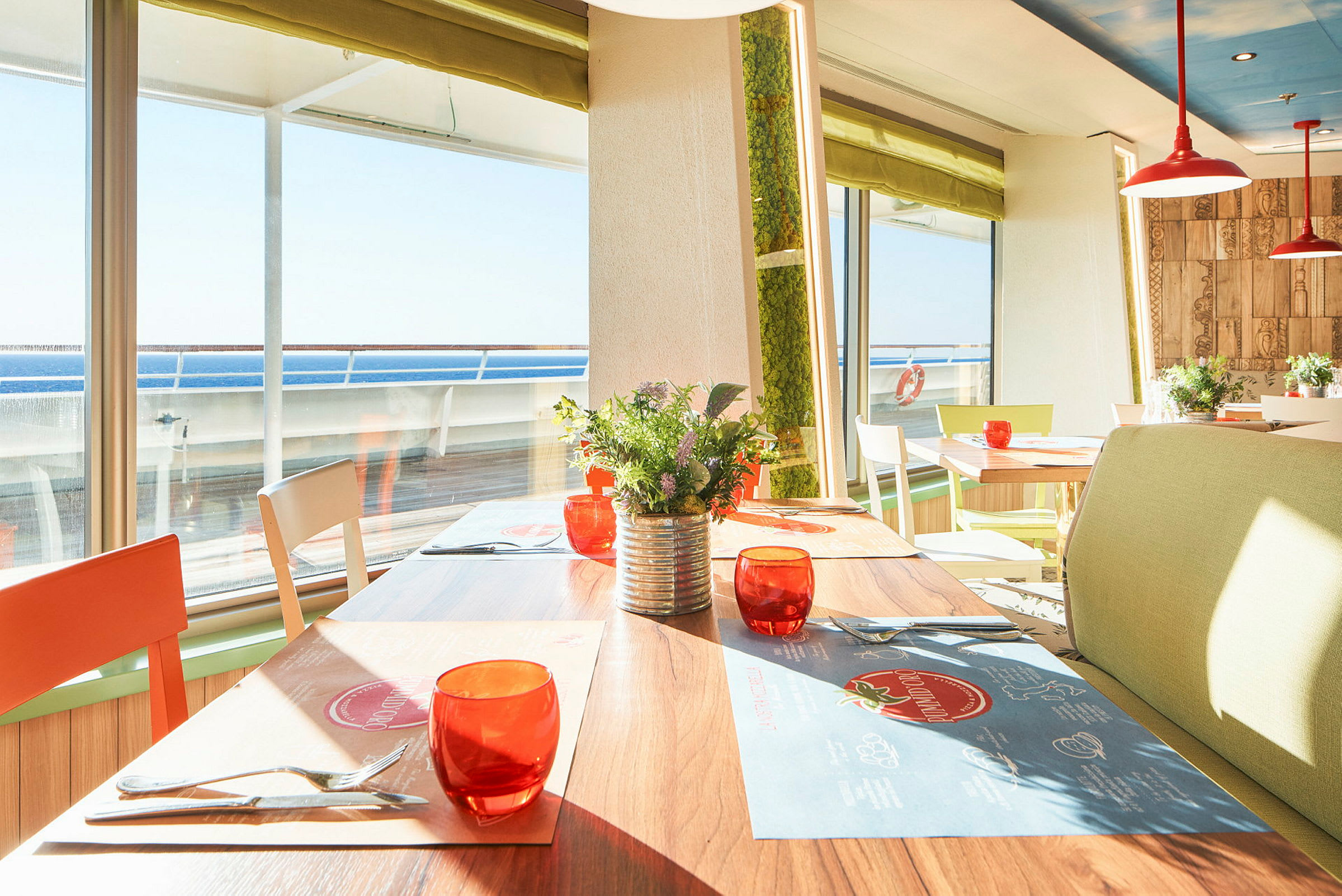 Solfylt restaurant med bord, stoler og utsikt til havet. (AI-generert tekst)