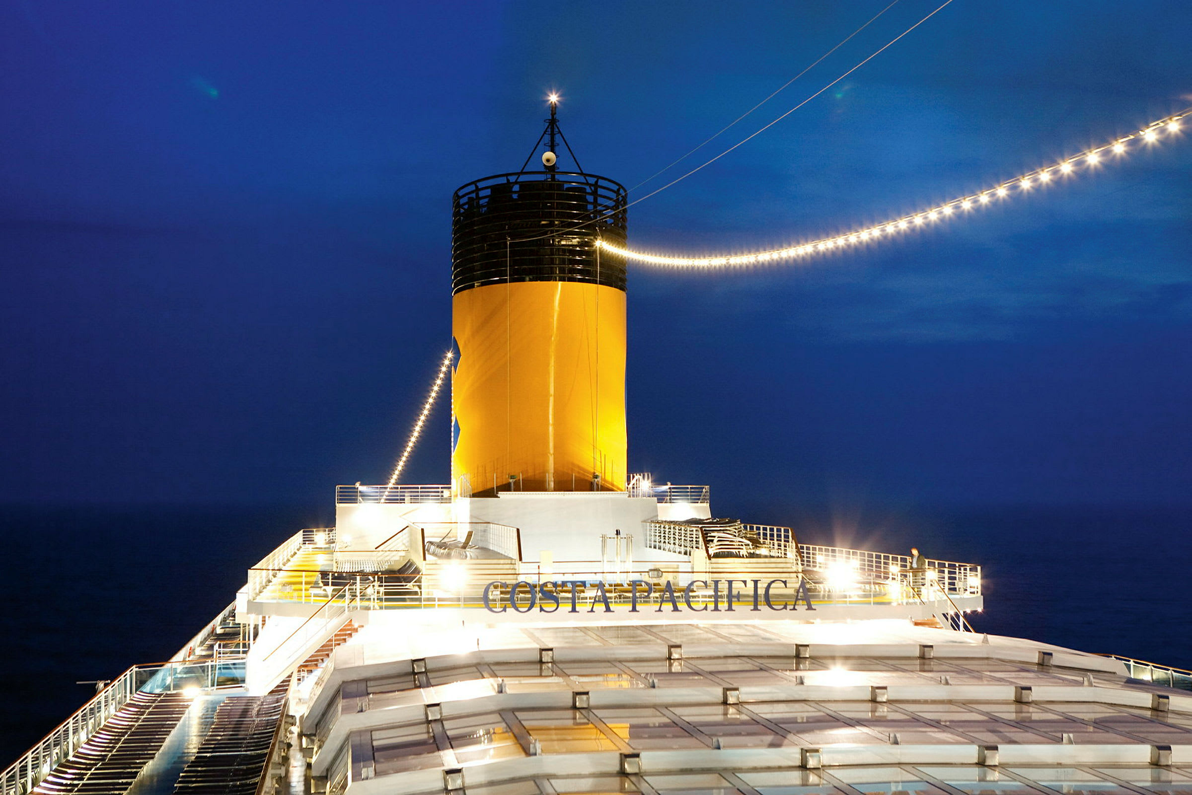 Bilde av skorsteinen på et cruiseskip med teksten 'Costa Pacifica' synlig om natten. (AI-generert tekst)