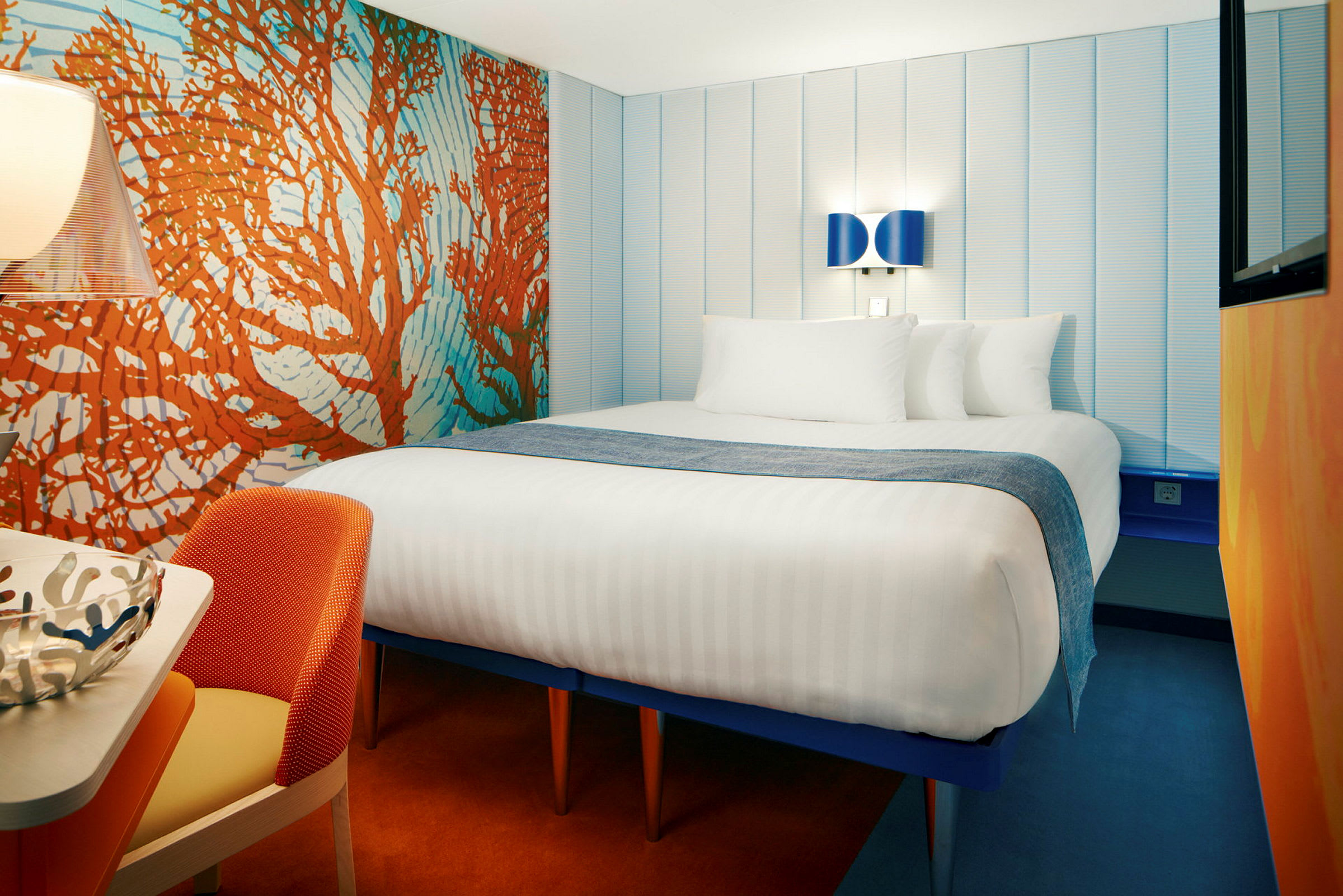 Hotellrom med en stor seng, fargerik innredning og moderne belysning. (AI-generert tekst)