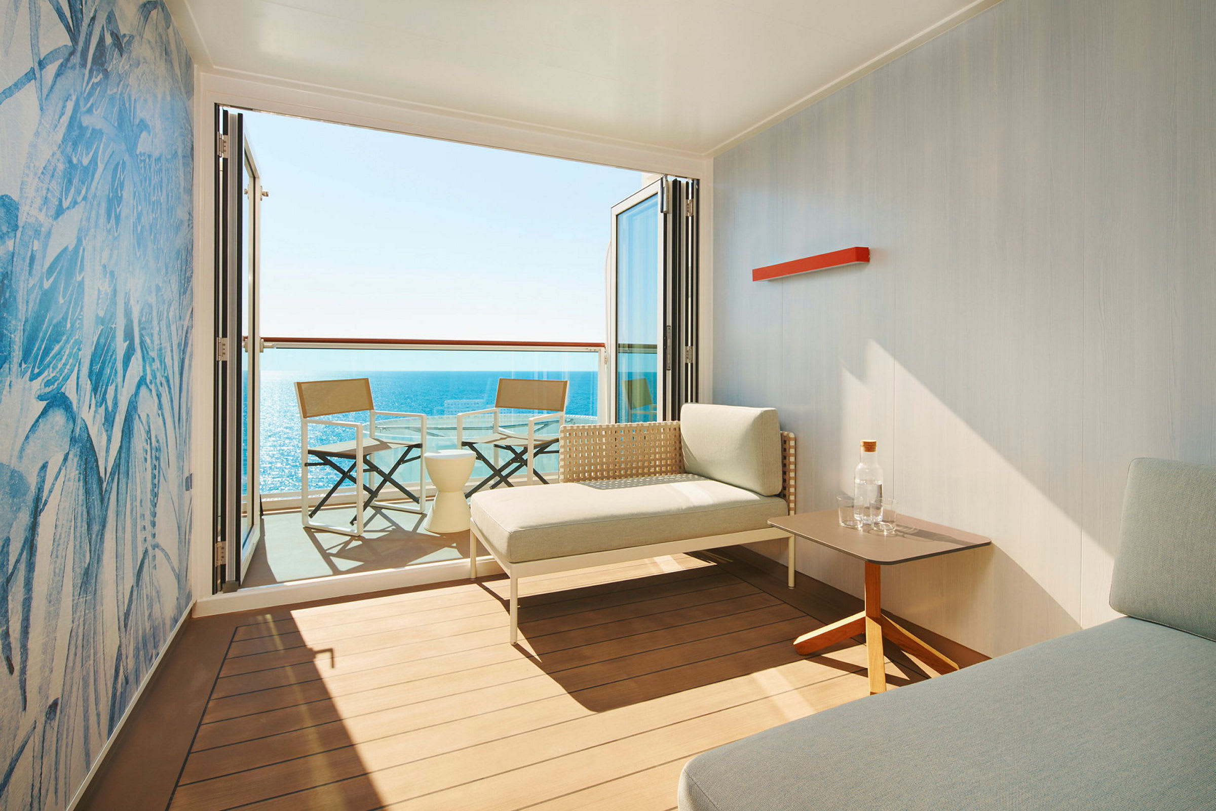 Et moderne hotellrom med en uteplass, to stoler og bord samt utsikt over havet. (AI-generert tekst)