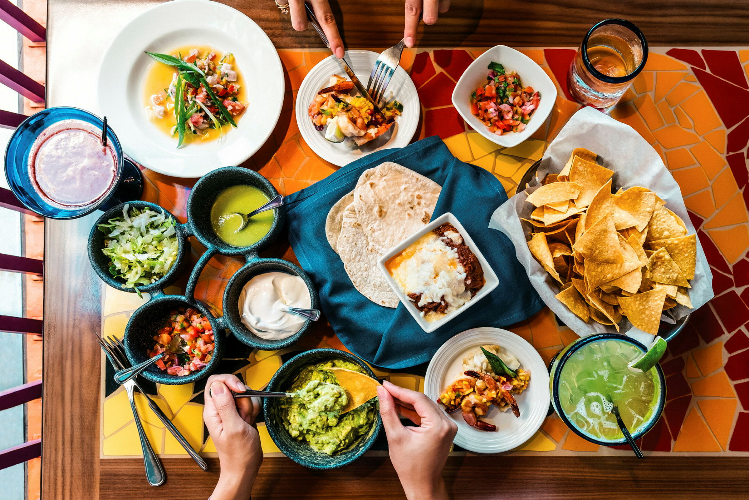 Et bord dekket med mexicansk mat, inkludert tacos, guacamole, chips og salsaer. (AI-generert tekst)