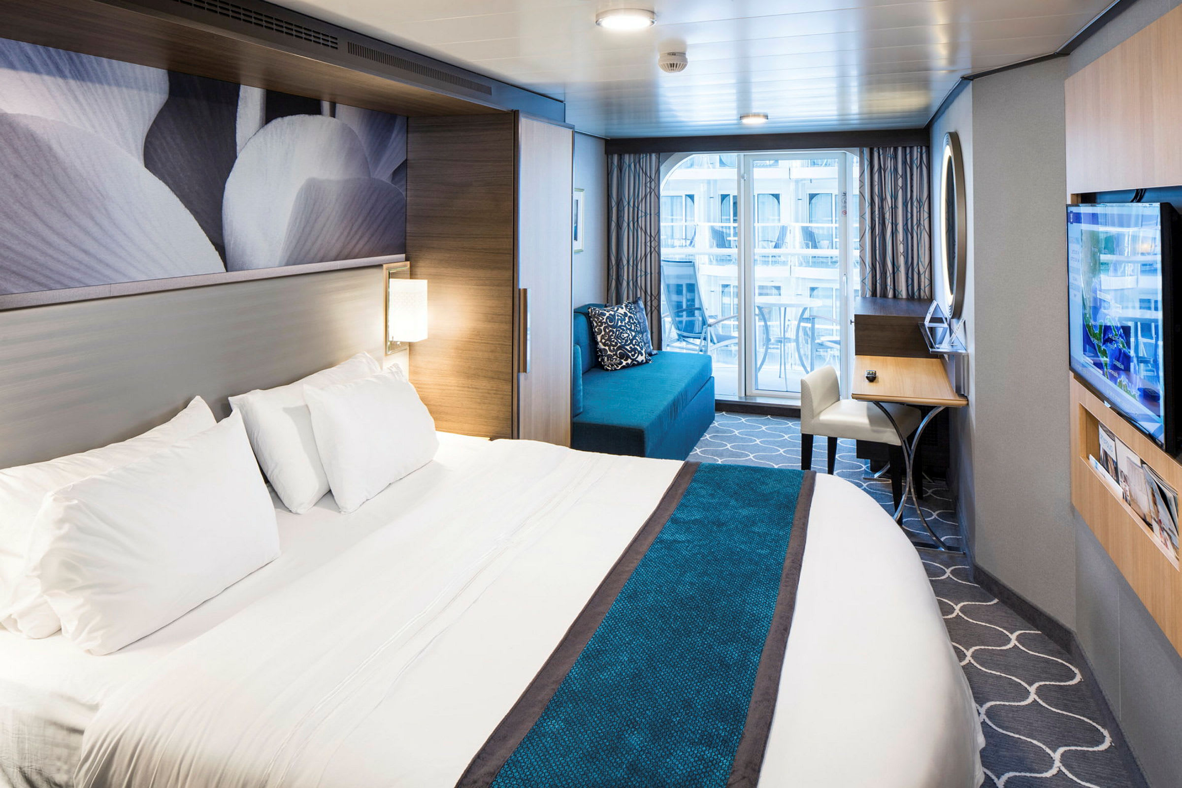 Hotellrom med en stor seng, sofa, skrivebord og balkong. (AI-generert tekst)
