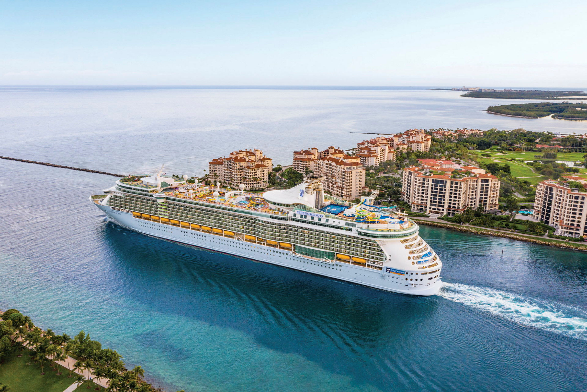 Et stort cruiseskip seiler forbi et boligområde med leilighetsbygninger ved vannet. (AI-generert tekst)