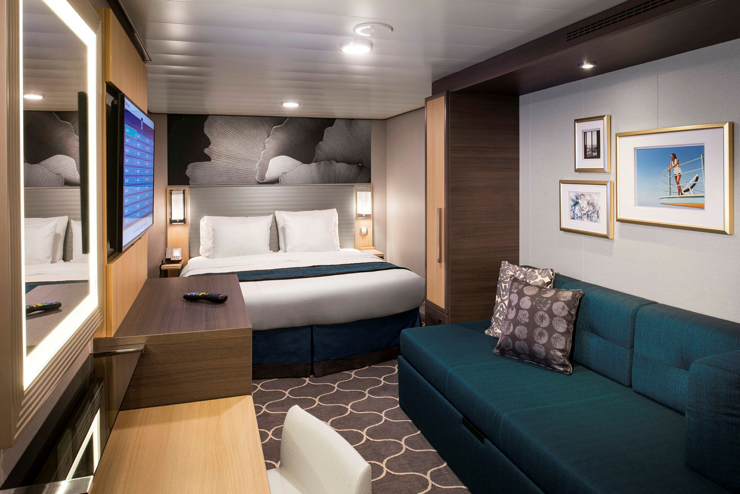 Et moderne hotellrom med en dobbeltseng, en sofa, veggdekorasjoner og et skrivebord med speil. (AI-generert tekst)