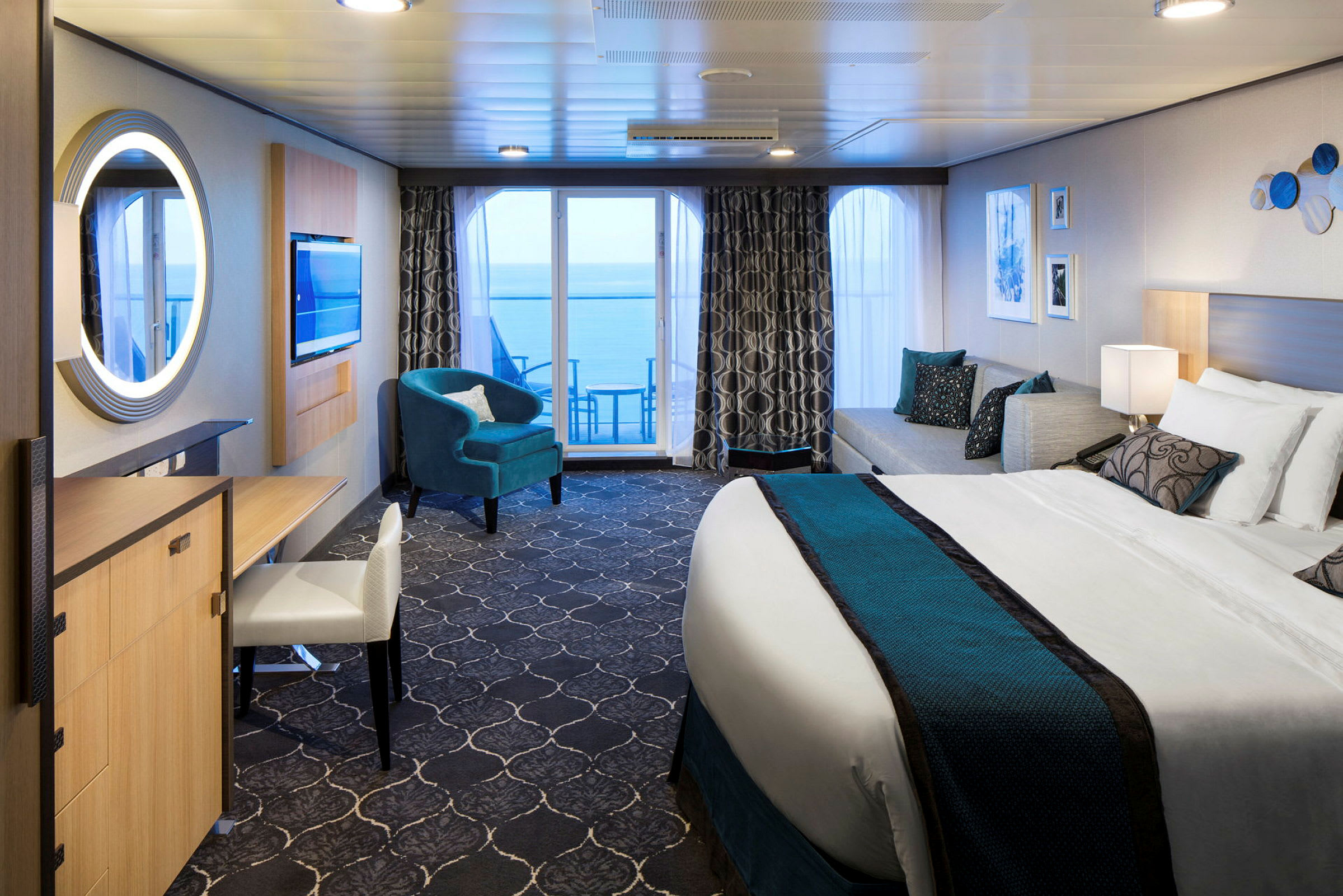 Et moderne hotellrom med stor seng, sittemøbler og balkong med havutsikt. (AI-generert tekst)