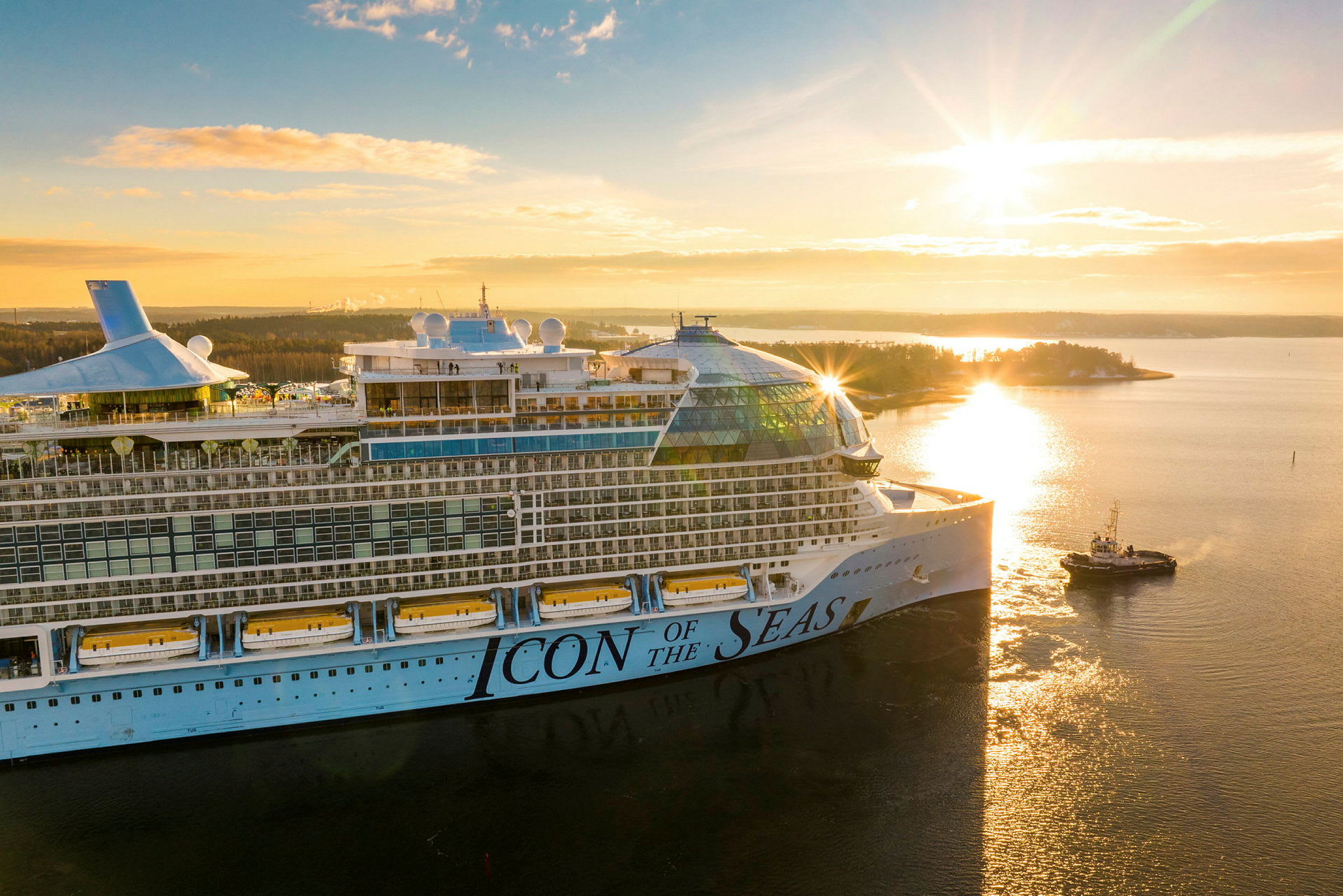 Et cruiseskip med teksten 'Icon of the Seas' på siden sees i soloppgang over en innsjø. (AI-generert tekst)