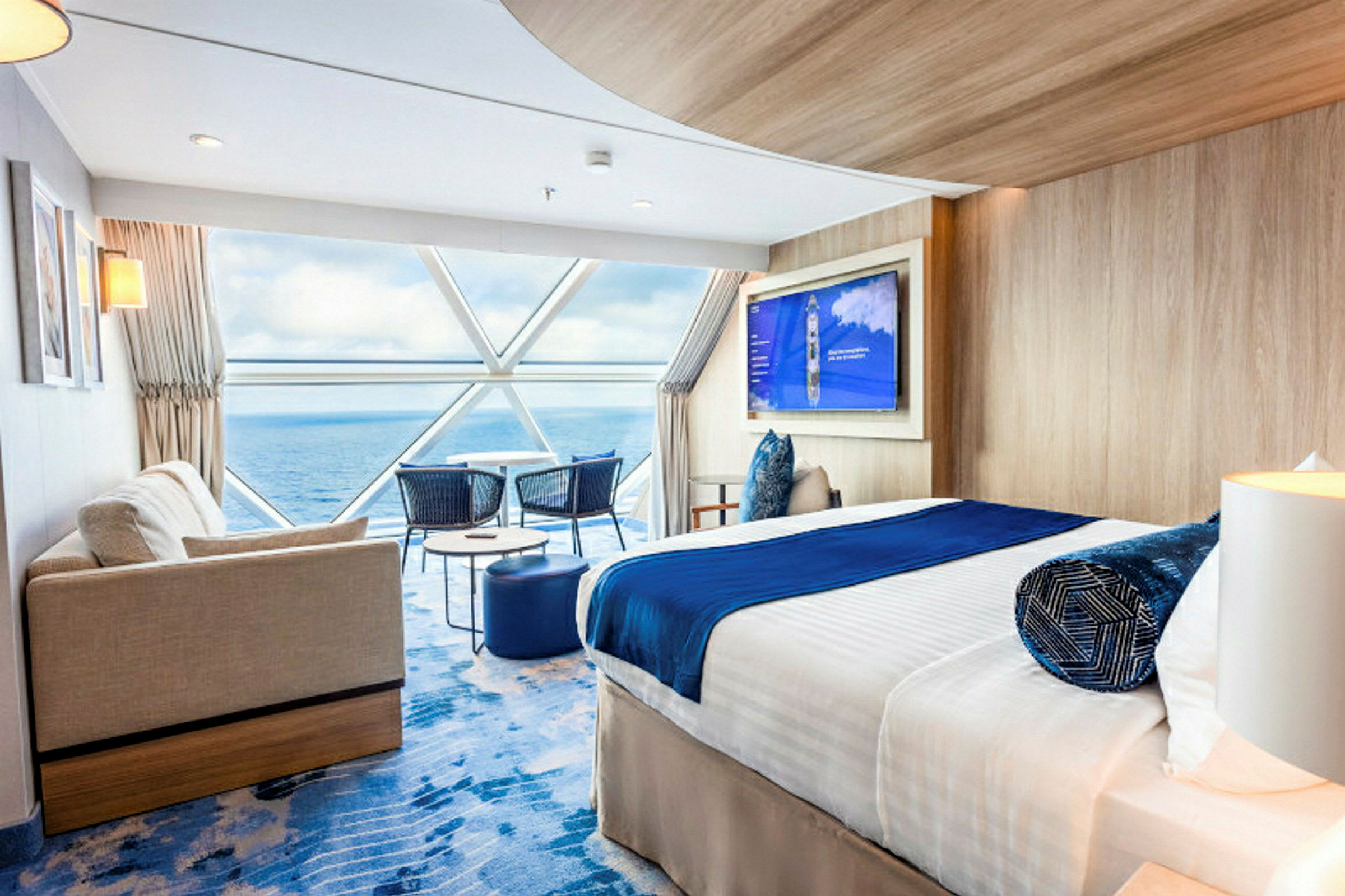 Moderne hotellrom med seng, sofa og utsikt over havet gjennom store vinduer. (AI-generert tekst)