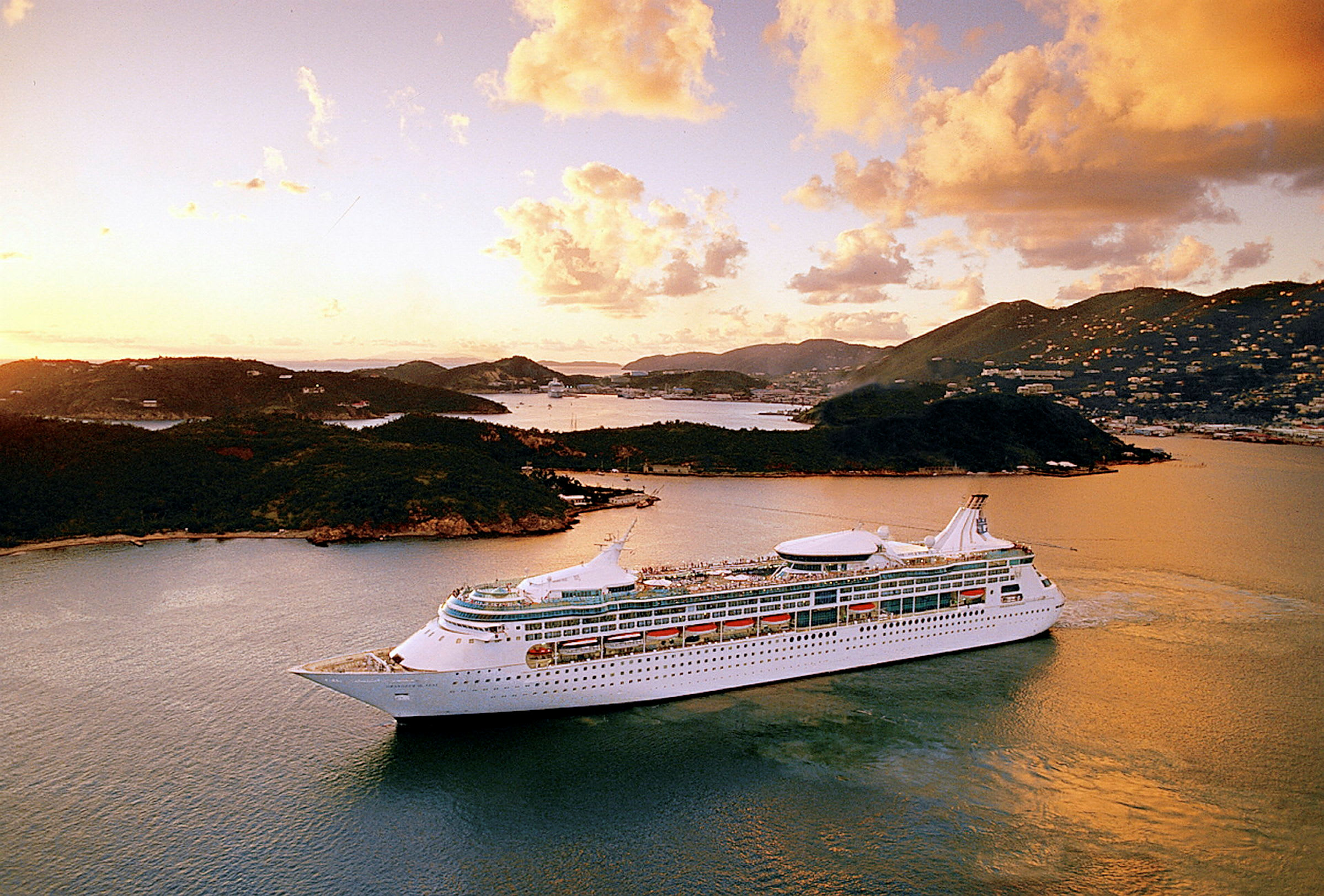 Et stort cruiseskip seiler i en solnedgang med øyer i bakgrunnen. (AI-generert tekst)