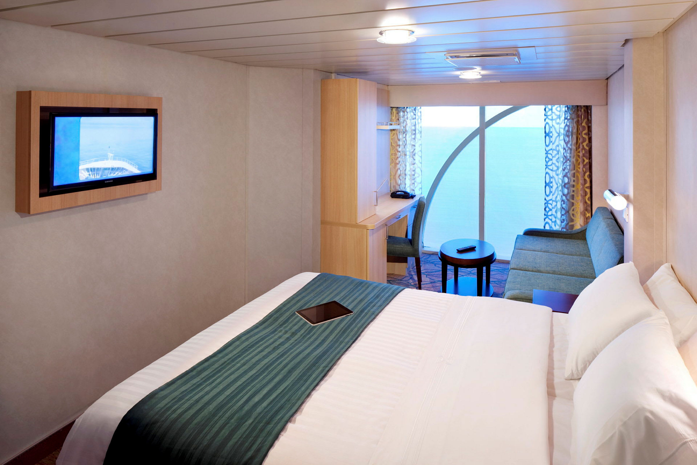 Et hotellrom med seng, sofa, TV og skrivebord. (AI-generert tekst)