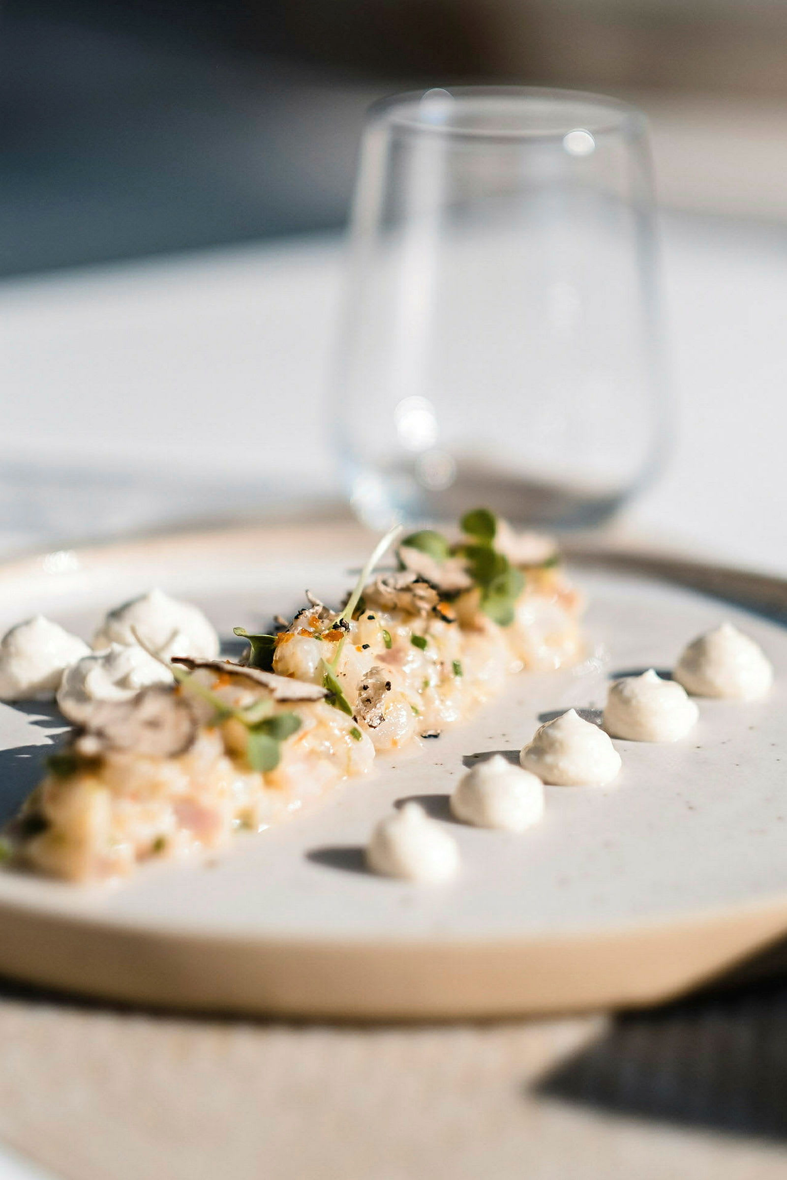 En tallerken med mat serveres elegant, med små klatter av en kremet saus og dekorasjoner. (AI-generert tekst)