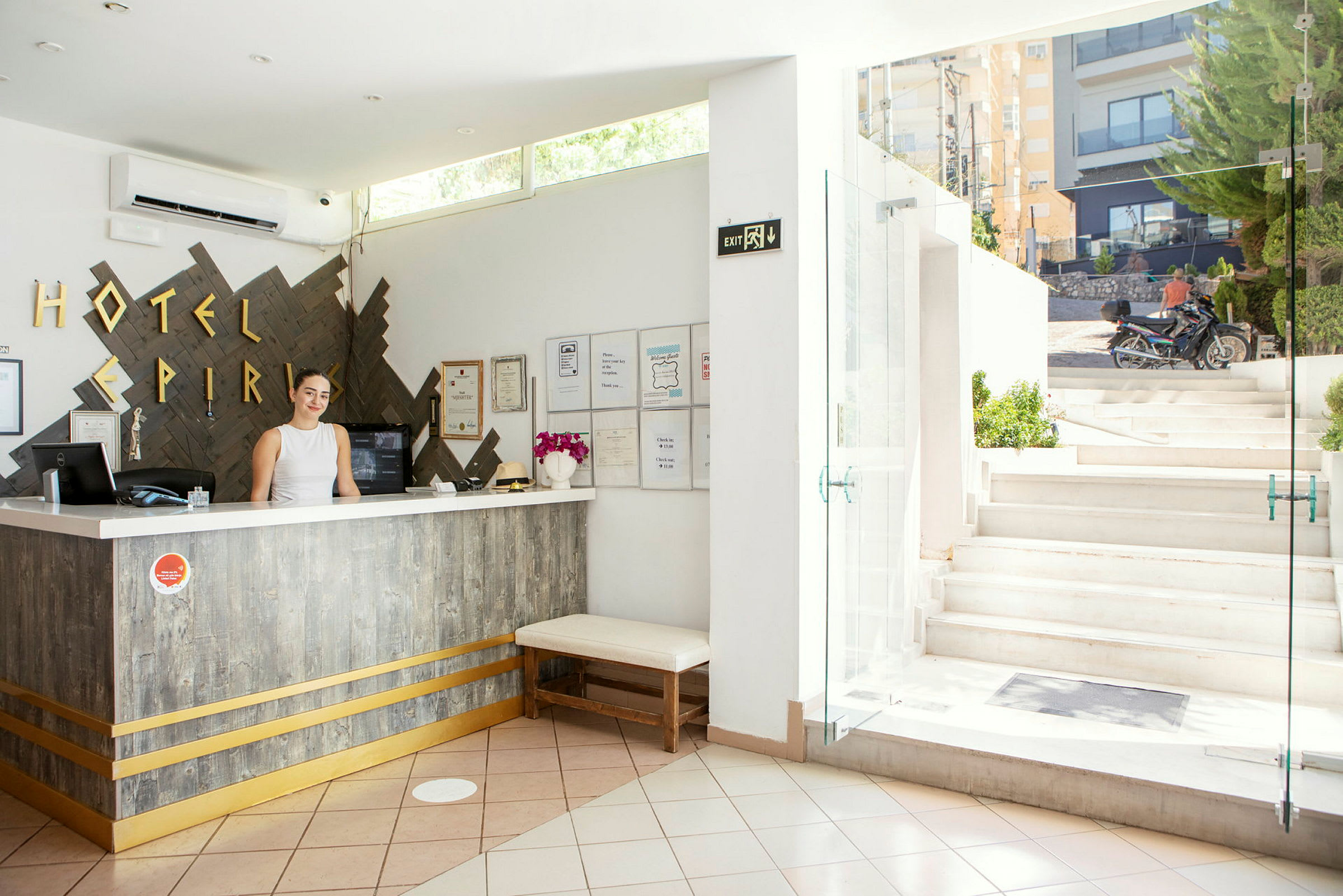 Hotellobby med resepsjon og åpning mot en utendørs trapp. (AI-generert tekst)