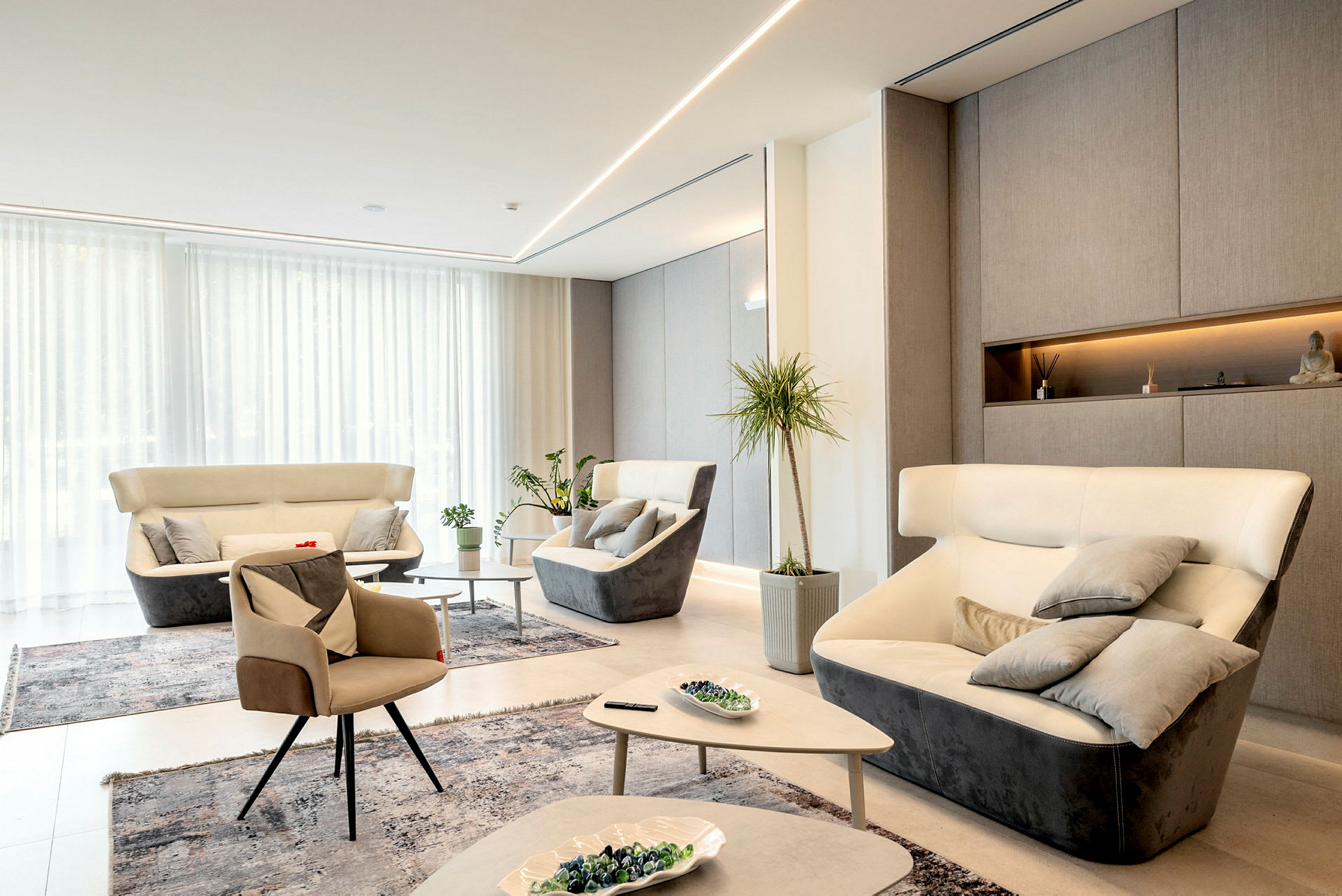 En moderne lounge med lys innredning, flere komfortable lenestoler og sofaer, planter og dekorative objekter. (AI-generert tekst)