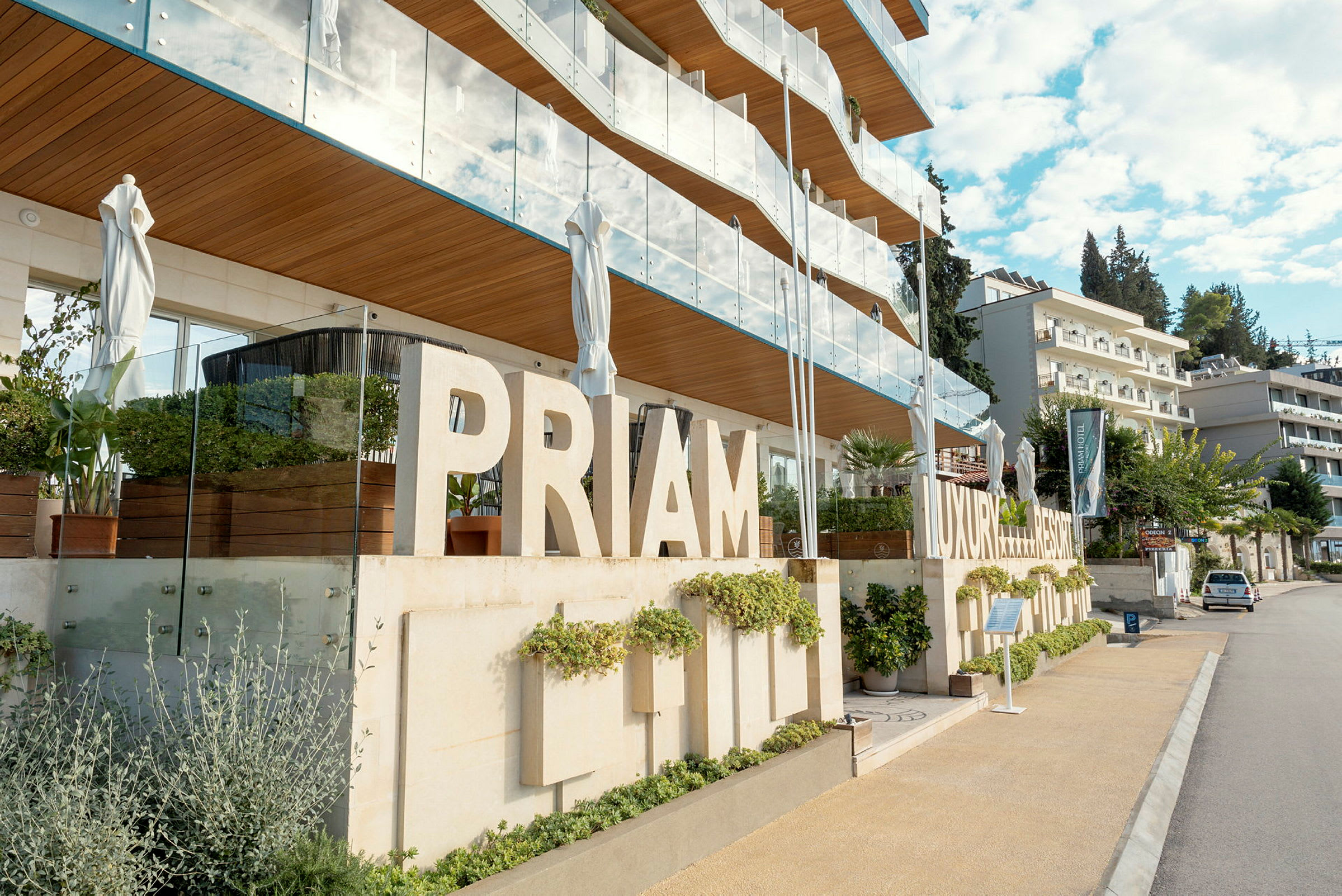 En moderne bygning med skilt som sier 'PRIMAM LUXURY RESORT', omgitt av grøntområder og balkonger. (AI-generert tekst)