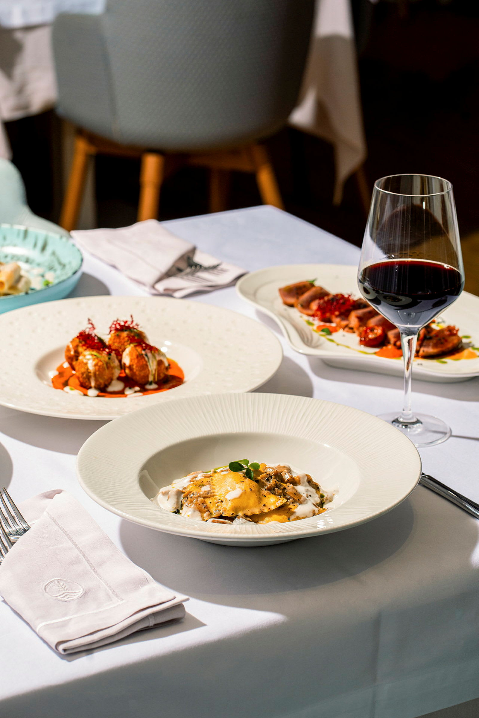 Et dekket restaurantbord med forskjellige matretter og et glass rødvin. (AI-generert tekst)