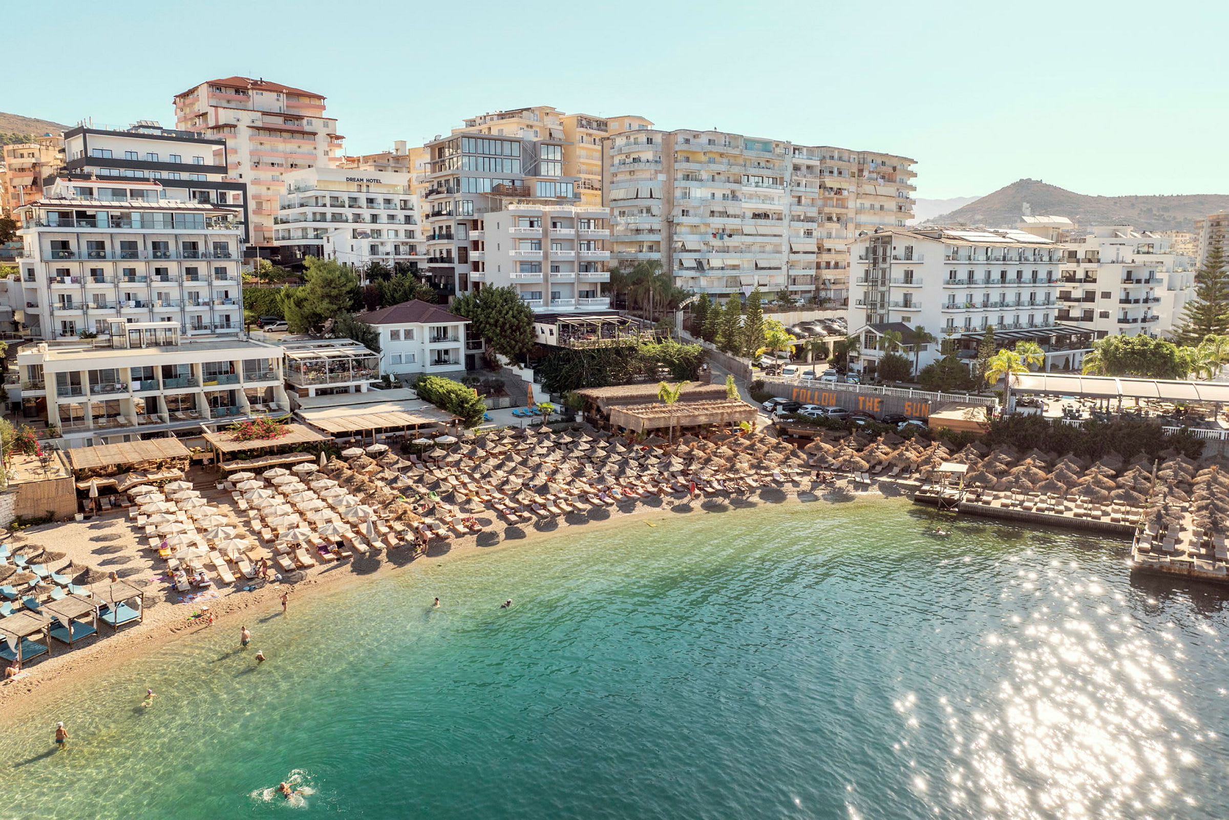 Hotell og parasoller ved en strand med klart vann. (AI-generert tekst)