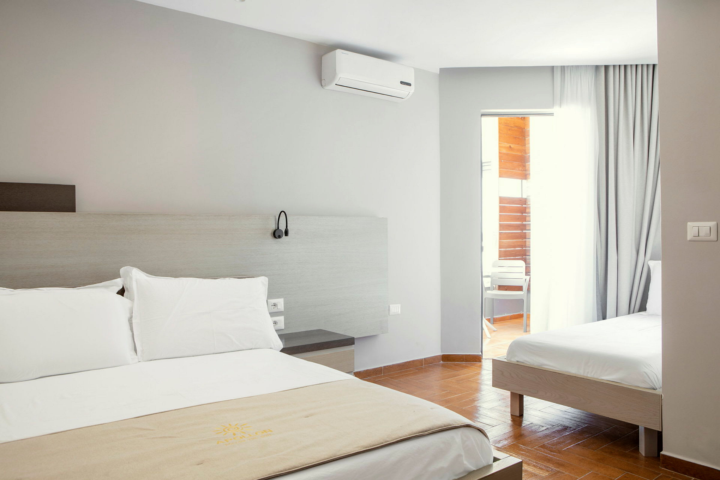 Hotellrom med to senger og en dør til balkongen. (AI-generert tekst)