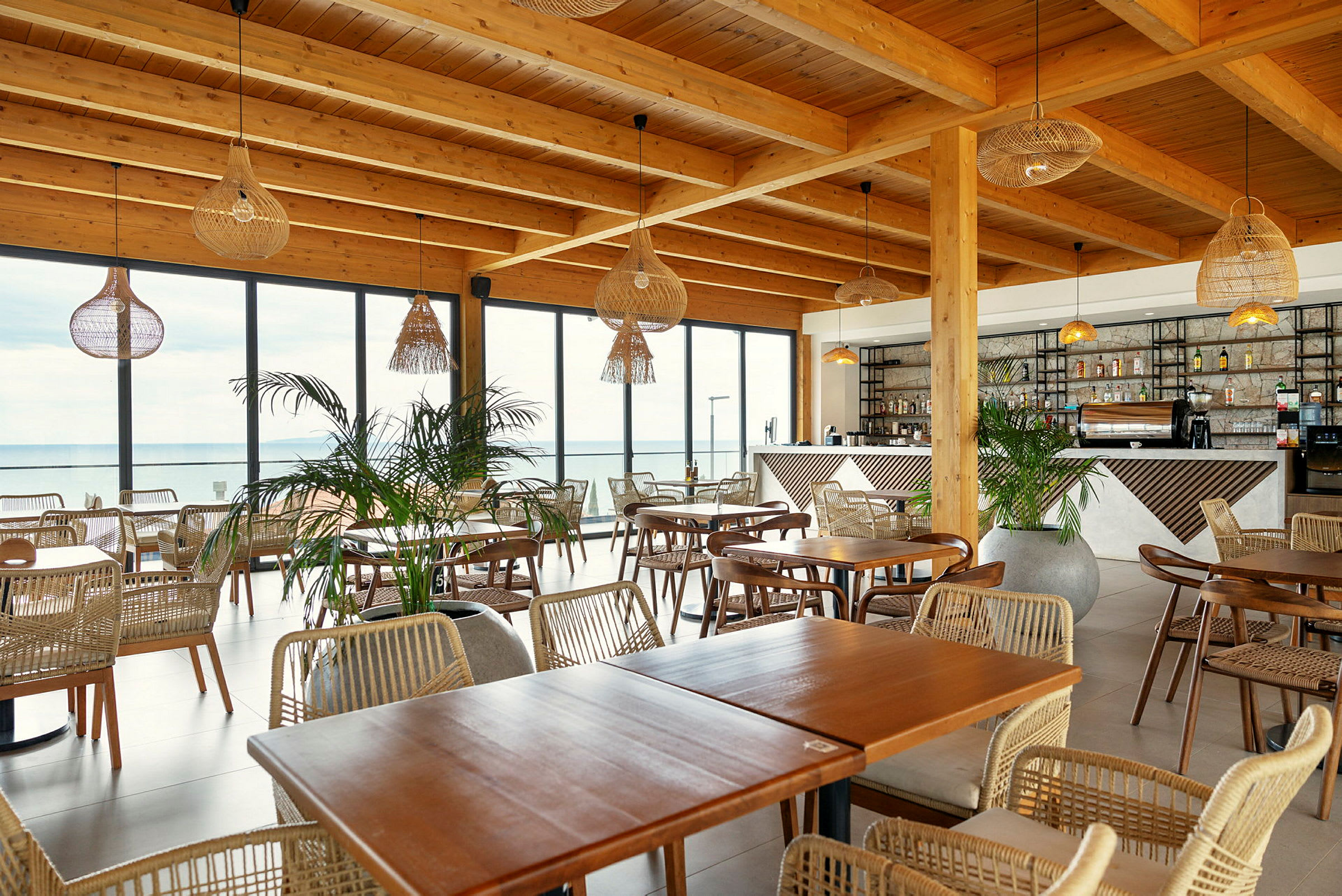 Restaurant med tremøbler, store glassvinduer og hengende lamper. (AI-generert tekst)
