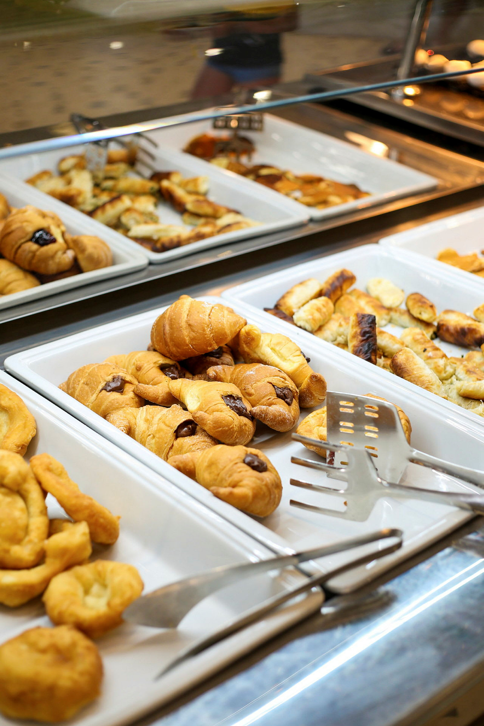 Utstilling med bakverk i ulike serveringsfat, inkludert croissanter. (AI-generert tekst)