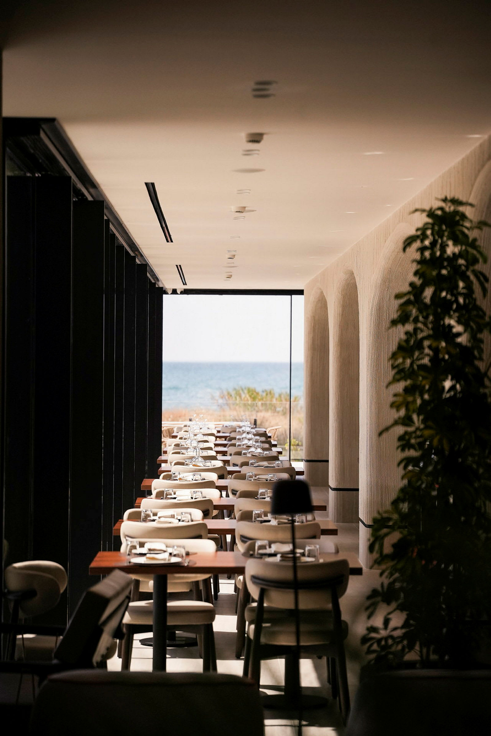 Et moderne innredet restaurantområde med dekkede bord og utsikt over havet i bakgrunnen. (AI-generert tekst)