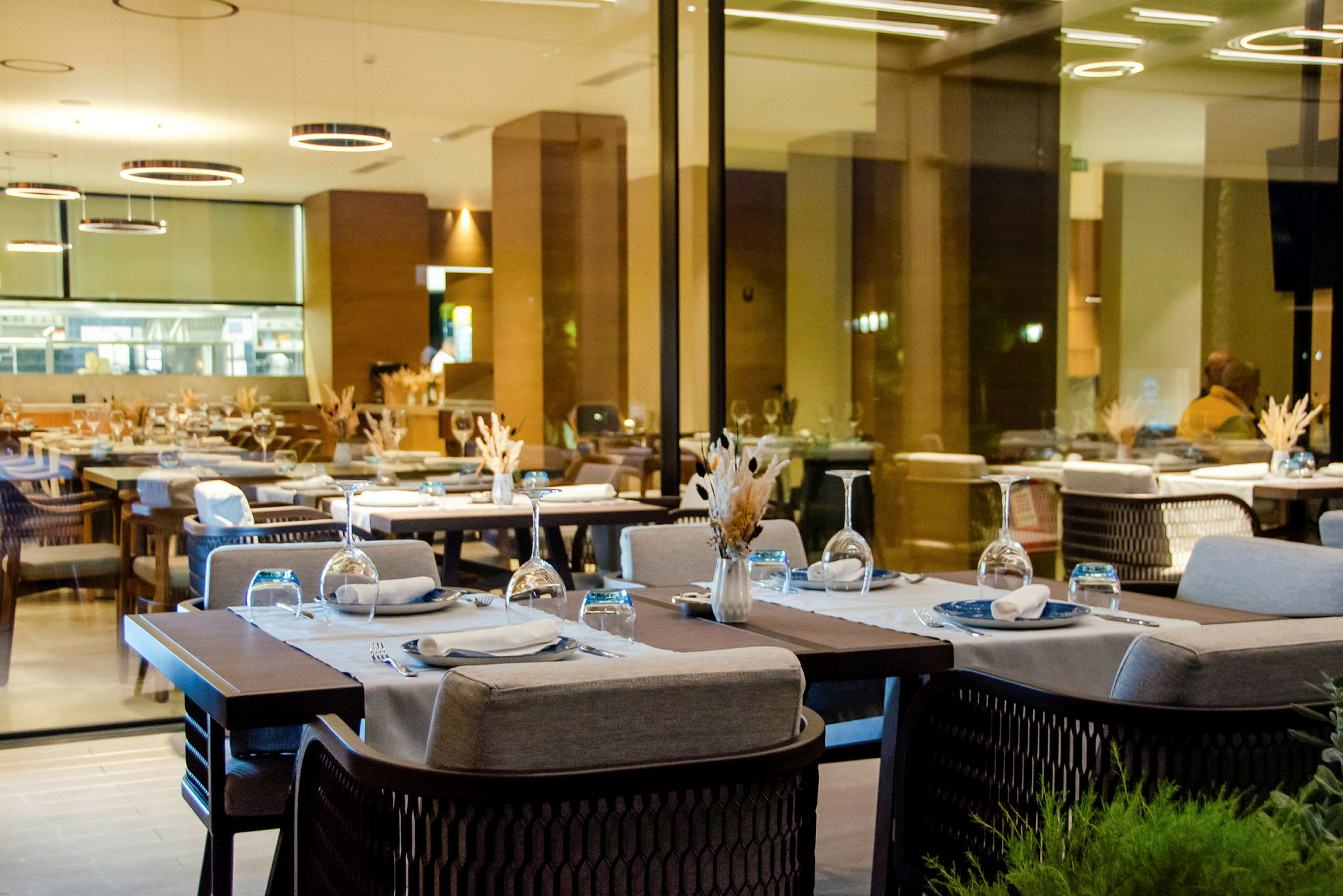 Bilde av en moderne restaurant med dekkede bord og glassvegger. (AI-generert tekst)