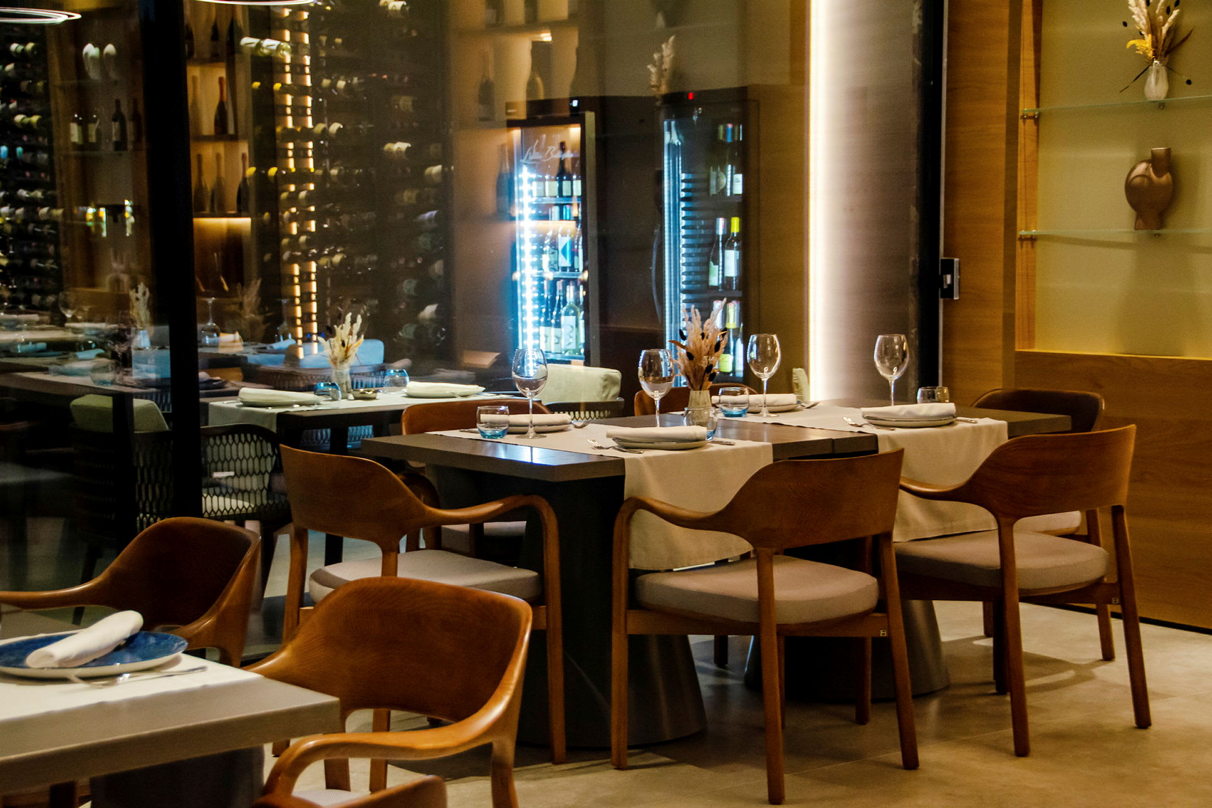 En elegant og moderne restaurant med oppdekkede bord og vinlagring i bakgrunnen. (AI-generert tekst)