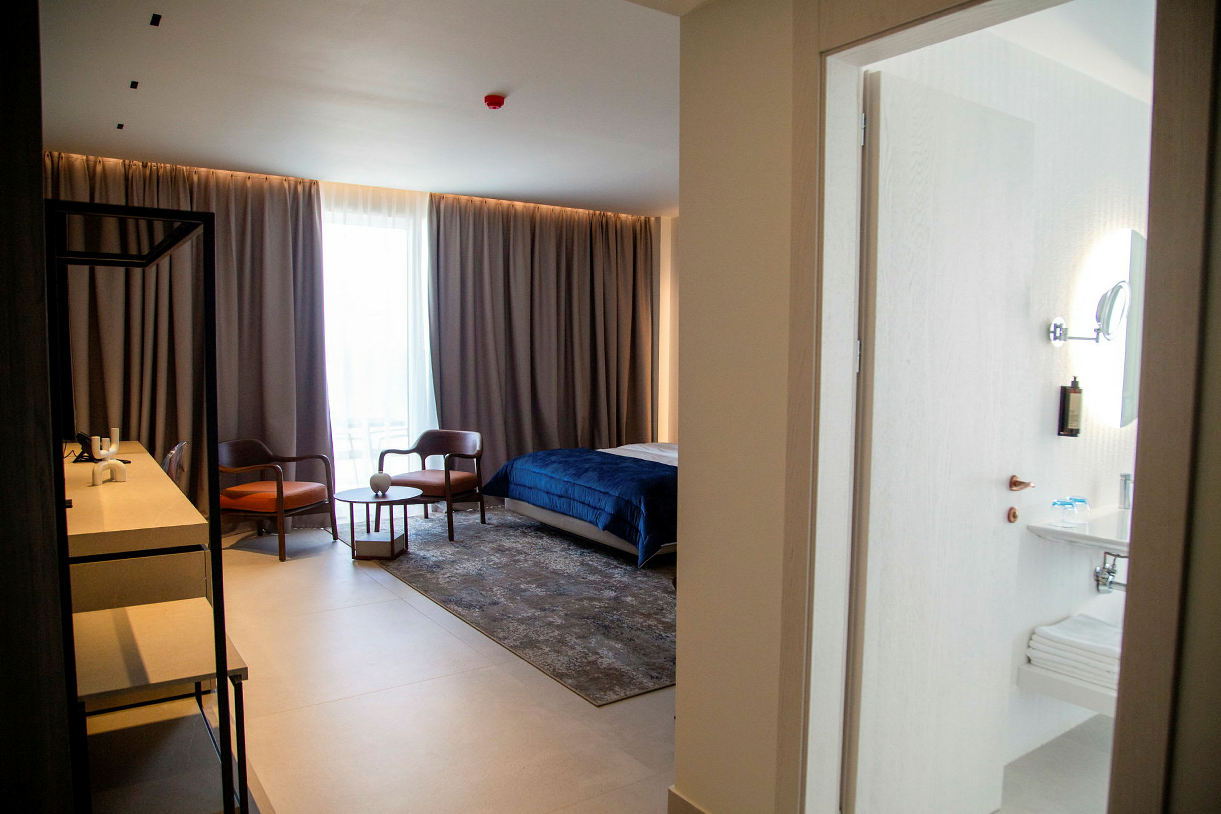 Hotellrom med seng, sittegruppe og skrivebord samt tilknyttet bad. (AI-generert tekst)