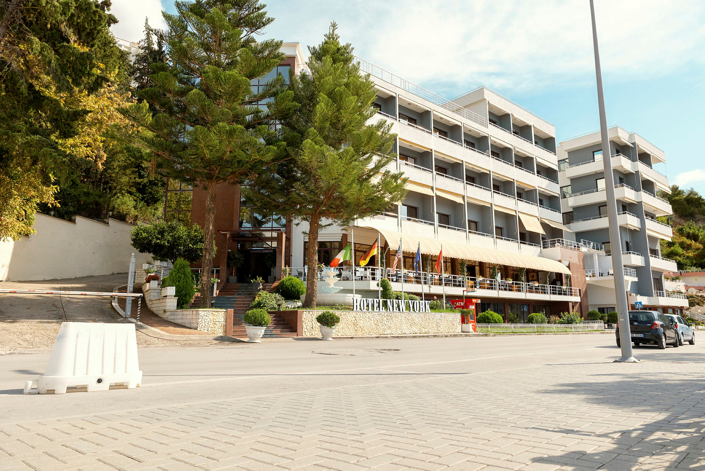 Hotel New York med flere etasjer og inngangsområde ved en vei. (AI-generert tekst)